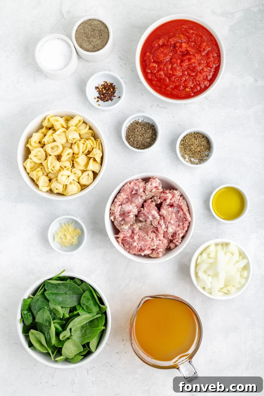 All the fresh ingredients for Sausage Tortellini Soup meticulously arranged in individual serving bowls on a clean white table, ready for cooking