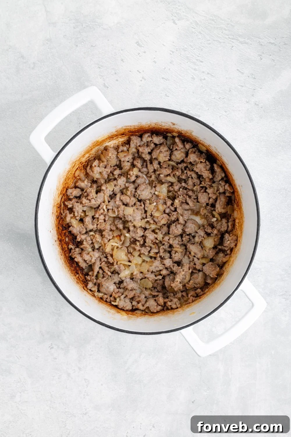 Perfectly cooked ground Italian sausage resting in a white pot on a clean white table