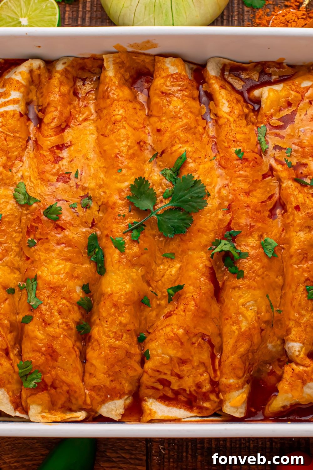 a casserole pan full of Steak Enchiladas  on wooden table with chopped cilantro on top 