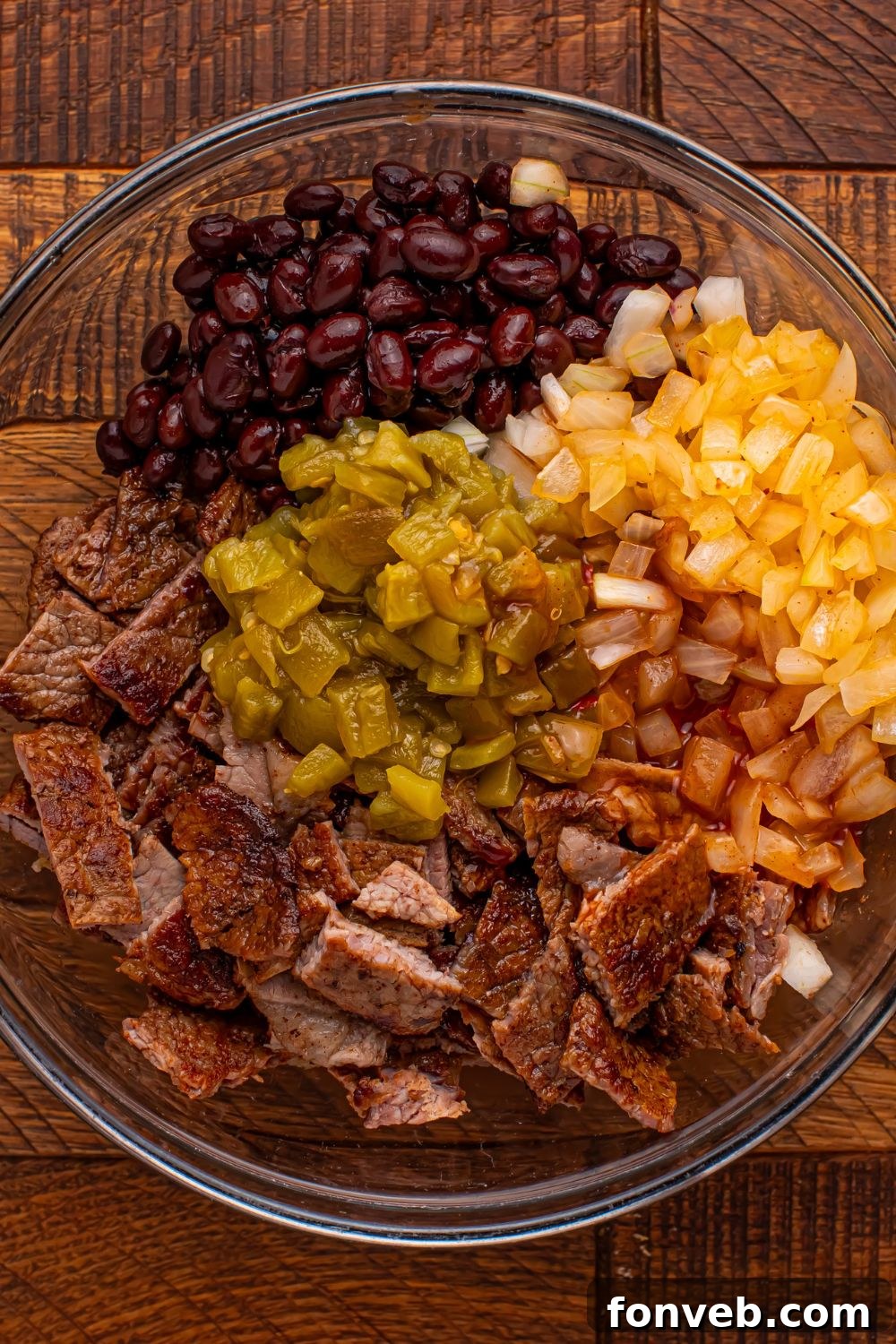 steak mixture in a glass bowl on wooden table for making Steak Enchiladas