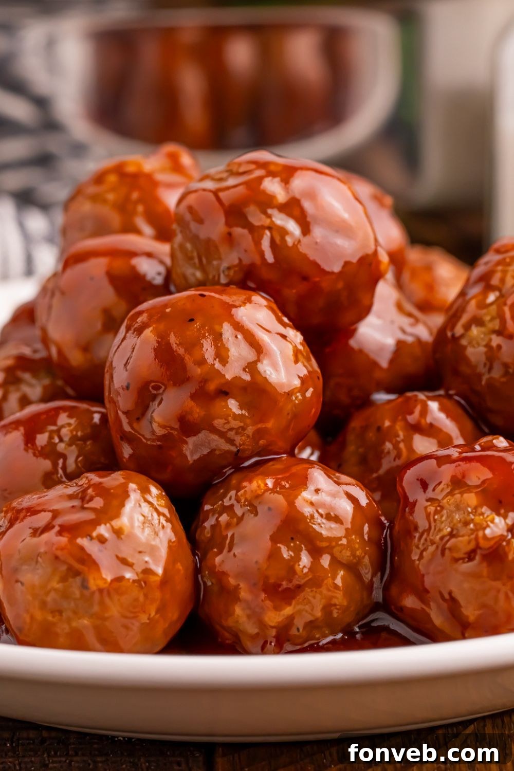 close up look of a stack of Peach BBQ Meatballs on a plate showing all the glaze coating each meatball