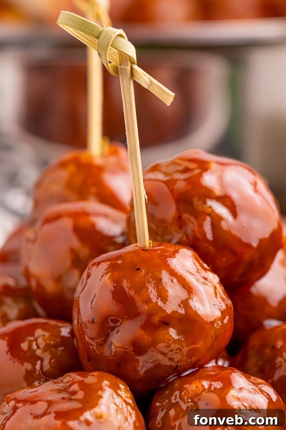 Peach BBQ Meatballs with toothpicks on it sitting in a pile on a plate 
