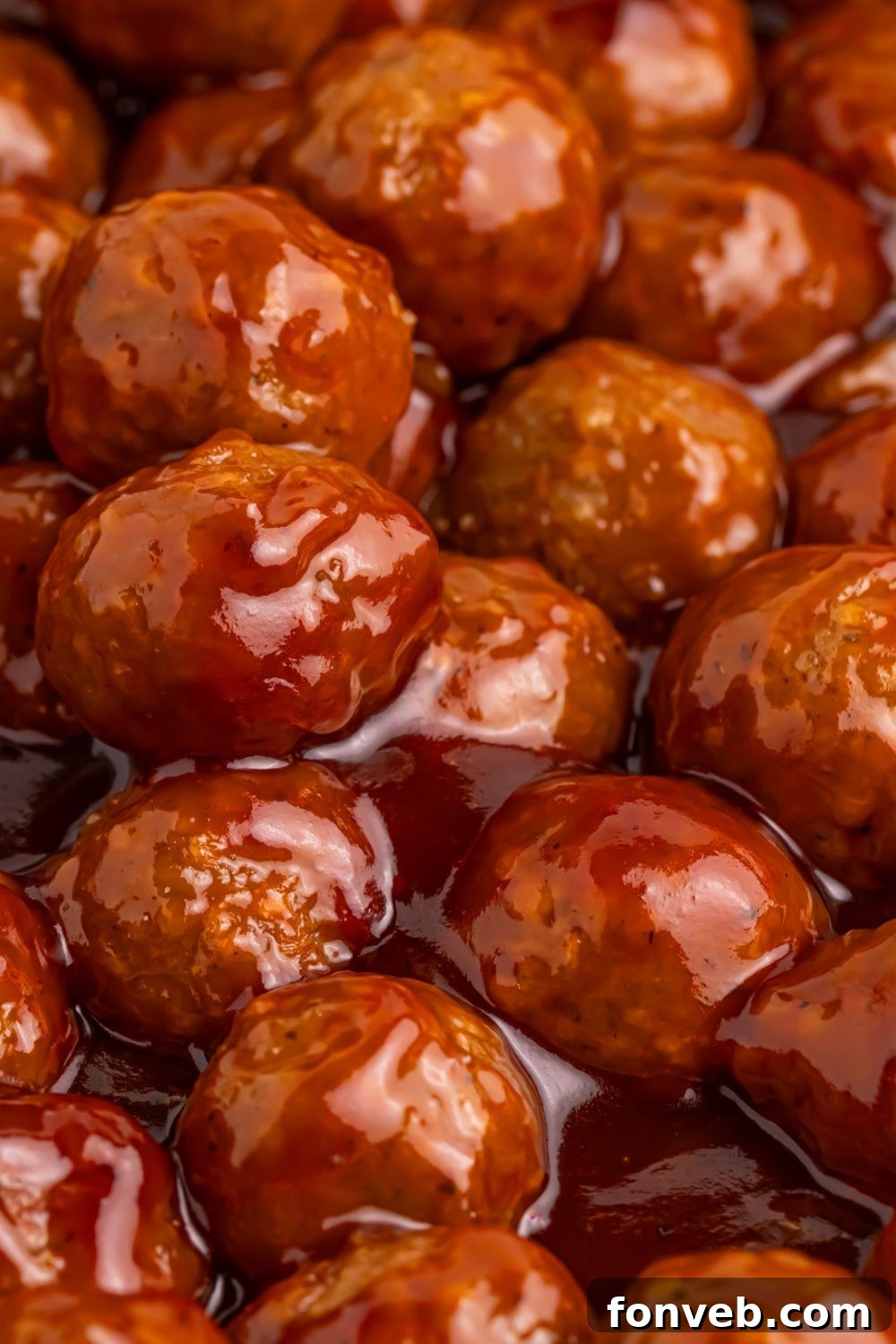 Peach BBQ Meatballs being cooked in a skillet full of sauce 