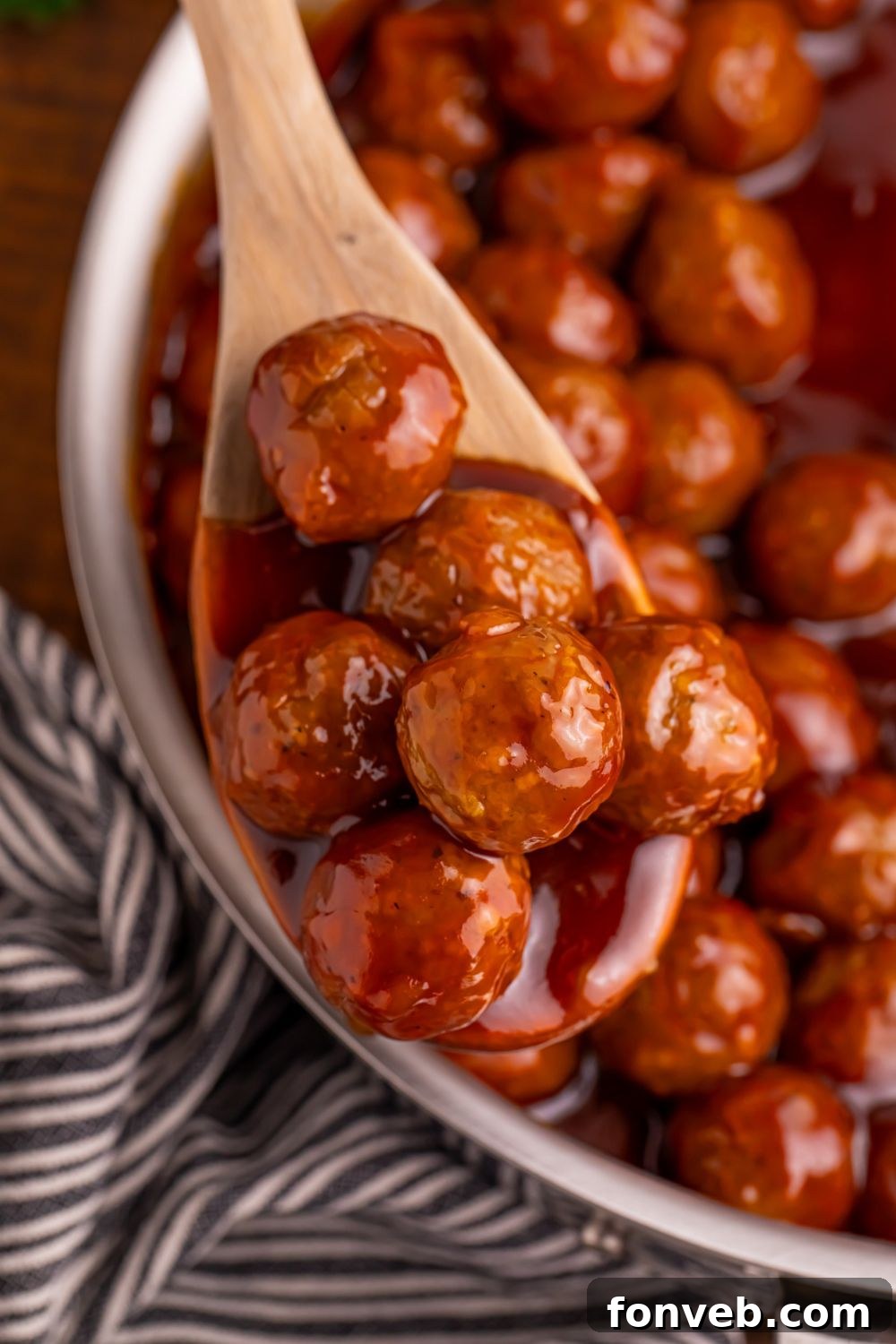 Peach BBQ Meatballs on a wooden spoon in a skillet 