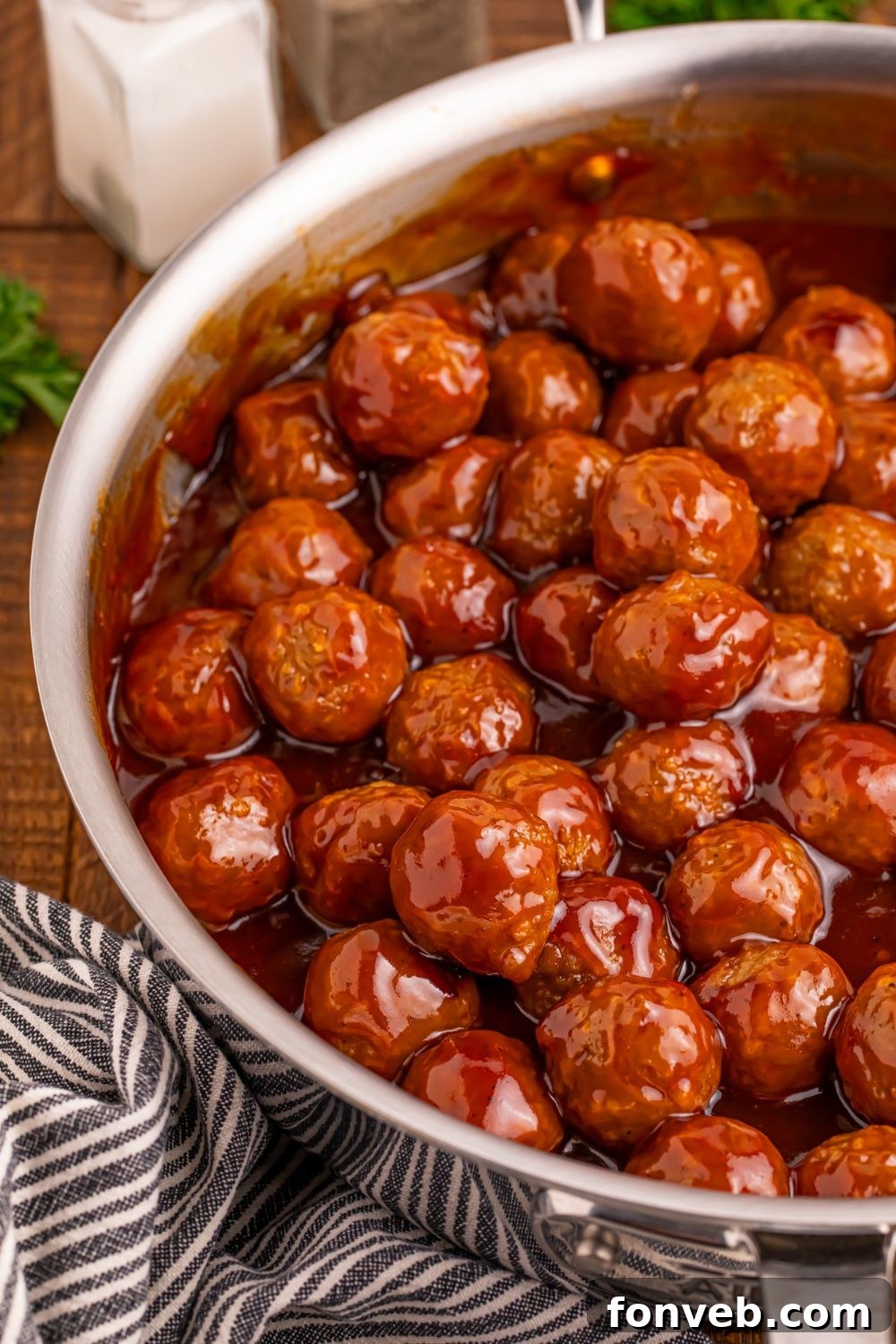 Peach BBQ Meatballs in a skillet on the table with a towel bunched beside the pan 