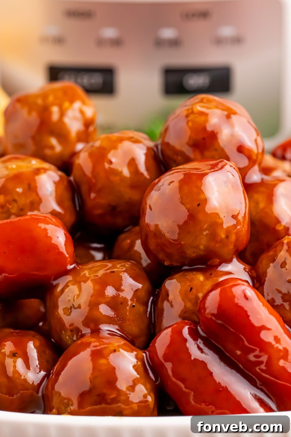 Crockpot Teriyaki BBQ Cocktail Meatballs & Lil Smokies in a casserole bowl with the slow cooker sitting behind it on the table 