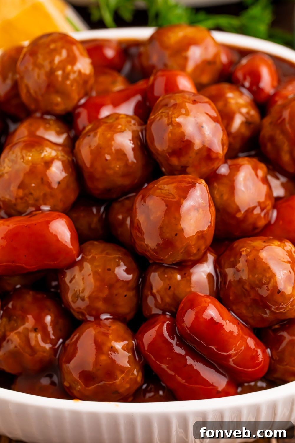 close up look of Crockpot Teriyaki BBQ Cocktail Meatballs & Lil Smokies piled on top of each other in a bowl on table 