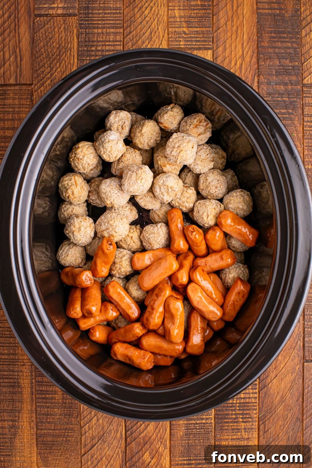frozen meatballs and little smokies in a crockpot sitting on the table