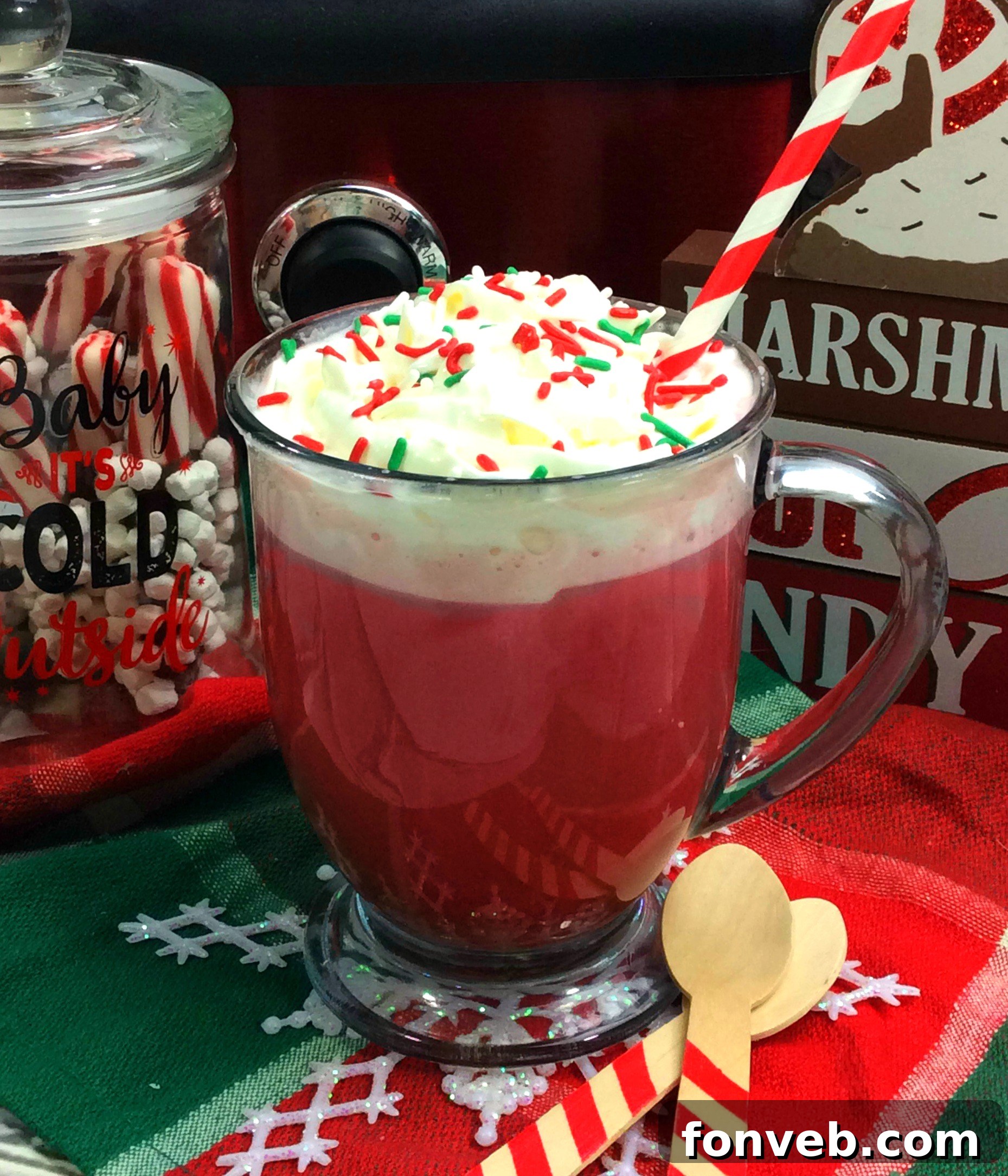Close-up of a mug filled with Red Velvet Hot Chocolate, topped with fluffy whipped cream and a sprinkle of chocolate shavings.