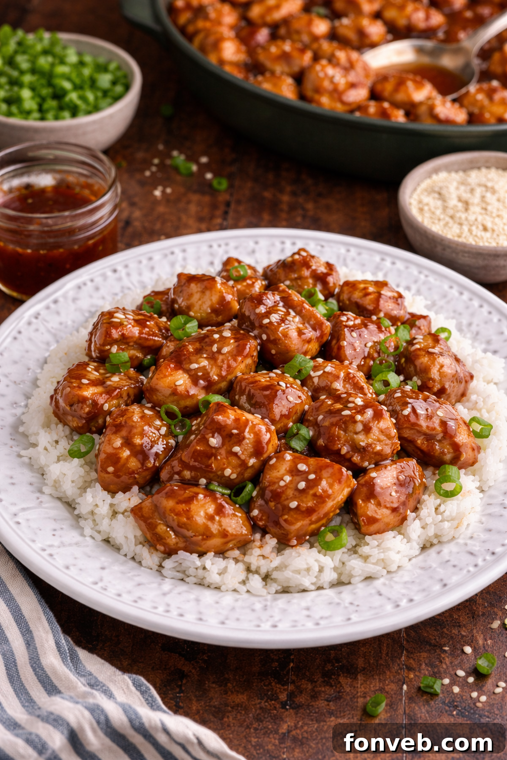 Irresistible Bourbon Chicken Skillet Quick Weeknight Win 2 Bourbon Chicken piled on top of a plate with some rice on the side and topped with sesame seeds and green onions