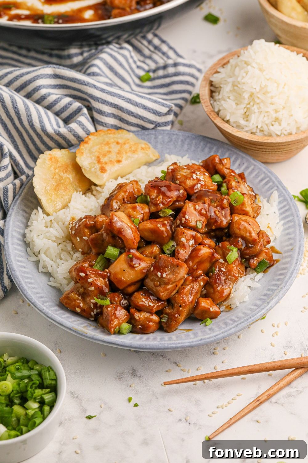 Irresistible Bourbon Chicken Skillet Quick Weeknight Win 17 a table full of bourbon chicken on plates, in a skillet, a bowl of green onions to the side, white rice in a bowl, and more
