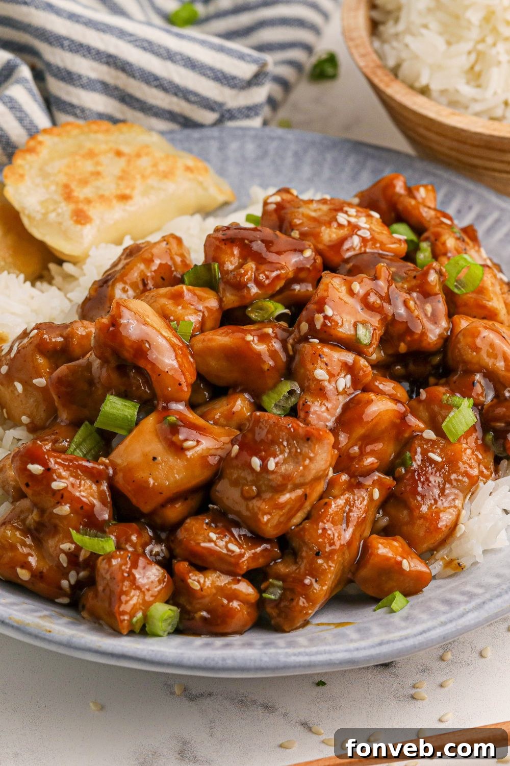 Irresistible Bourbon Chicken Skillet Quick Weeknight Win 19 a blue and white plate on table with diced bourbon chicken and white and pieorgies to the side on the the