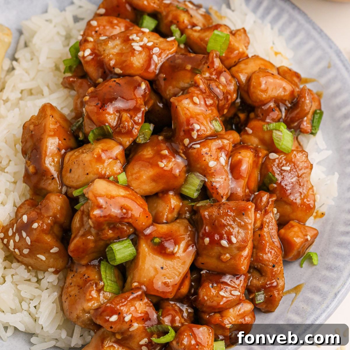 Irresistible Bourbon Chicken Skillet Quick Weeknight Win 3 Bourbon Chicken piled on top of a plate with some rice on the side and topped with sesame seeds and green onions
