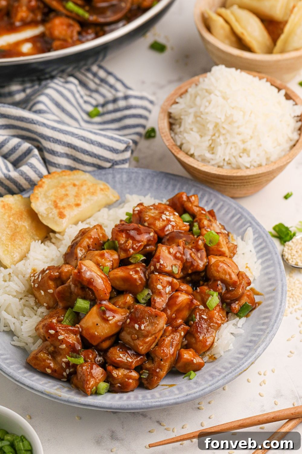 Irresistible Bourbon Chicken Skillet Quick Weeknight Win 4 Bourbon Chicken on a plate with rice to side and bread, with a bowl of rice and more chicken spread out on the table