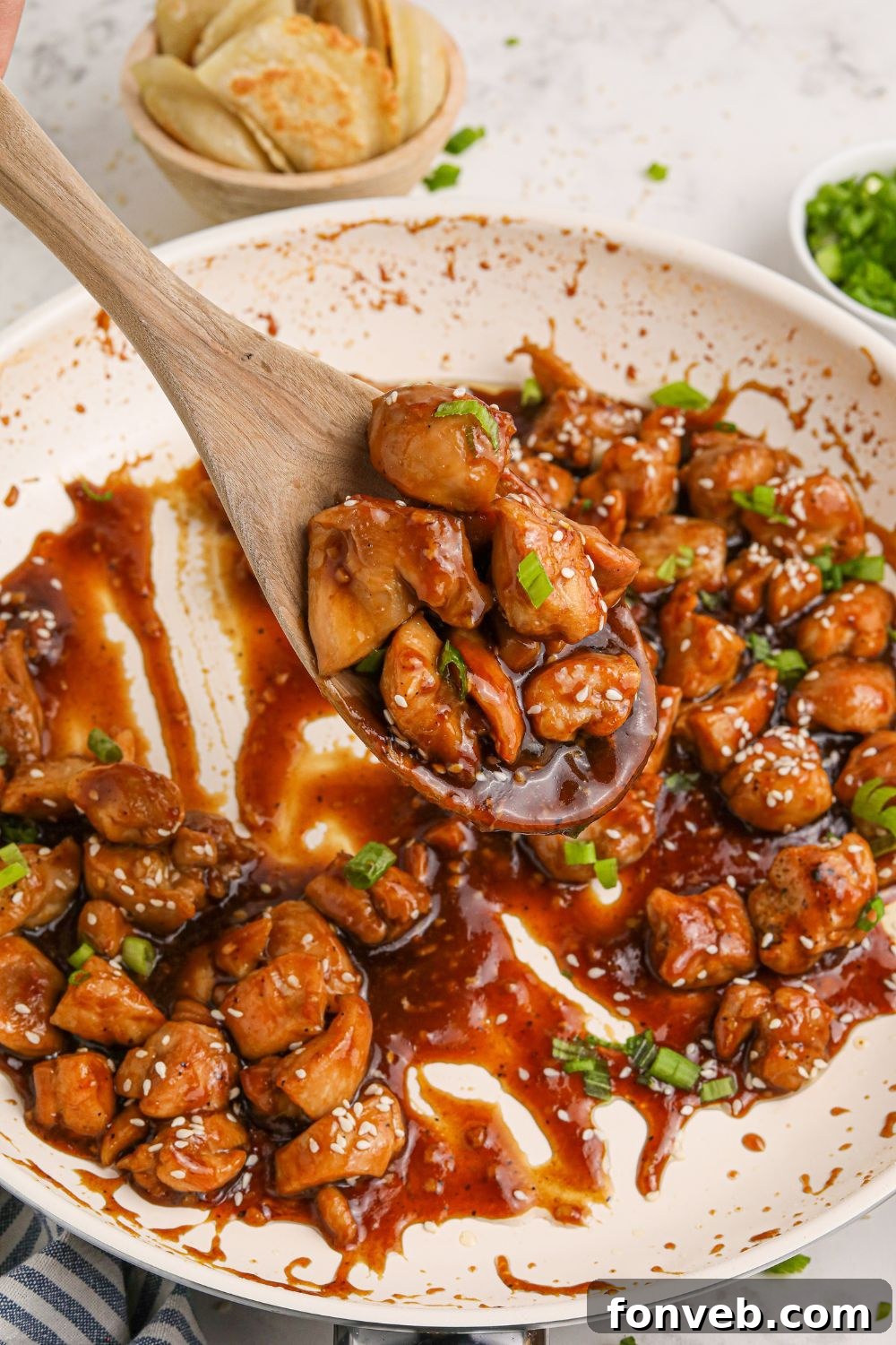 Irresistible Bourbon Chicken Skillet Quick Weeknight Win 10 skillet with Bourbon Chicken in it with sauce and a spoon scooping up the chicken
