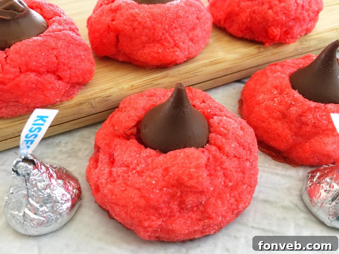 A close-up shot of a plate of vibrant red Cherry Kiss Cookies with Hershey's Kisses on top, ready to be enjoyed.