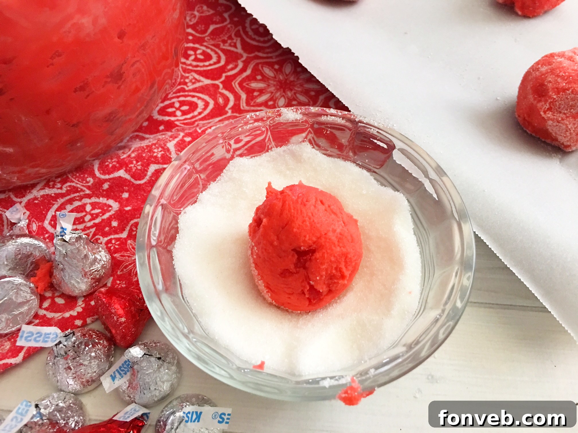 A close-up of a single Cherry Kiss Cookie, highlighting its vibrant red color and the perfectly placed Hershey's Kiss.