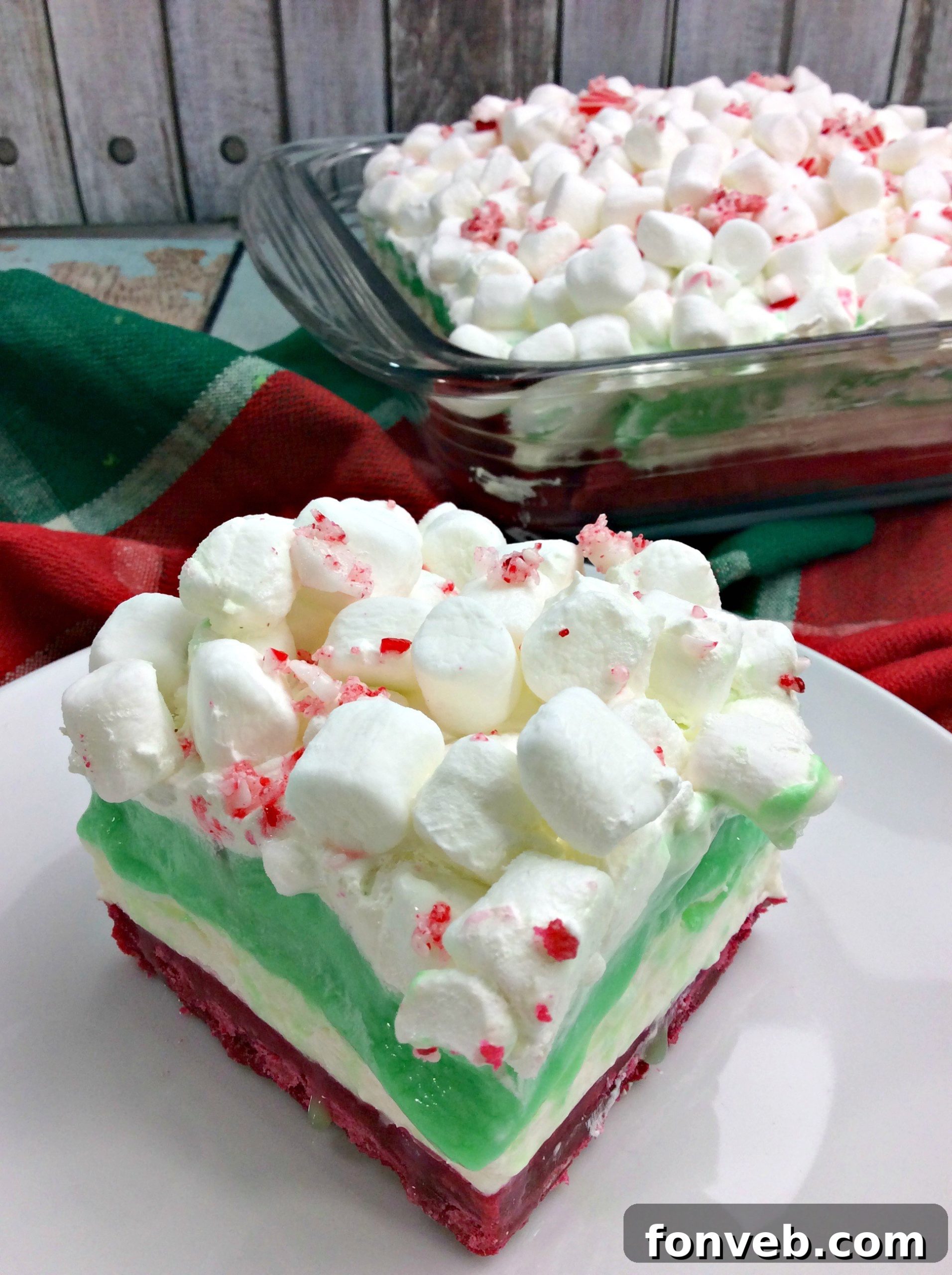 Close-up view of a perfectly sliced Christmas Cheesecake Lasagna, showcasing its distinct, colorful dessert layers