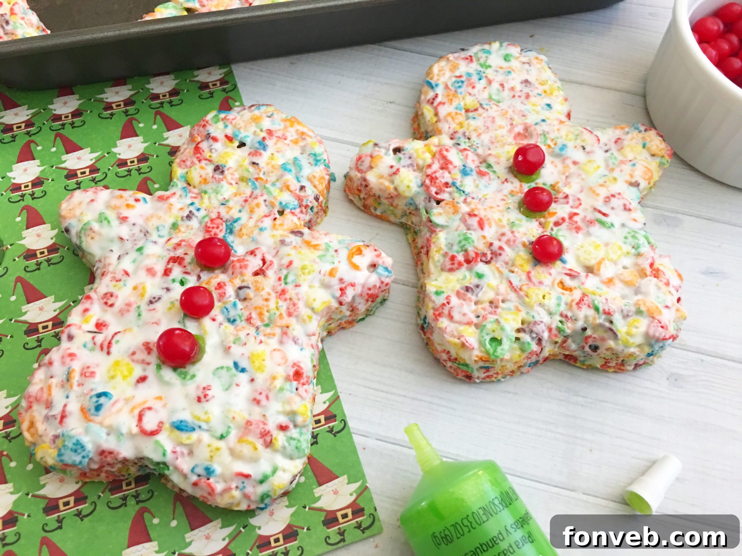 Multiple gingerbread-shaped Fruity Pebbles treats, some decorated, arranged on a baking sheet.
