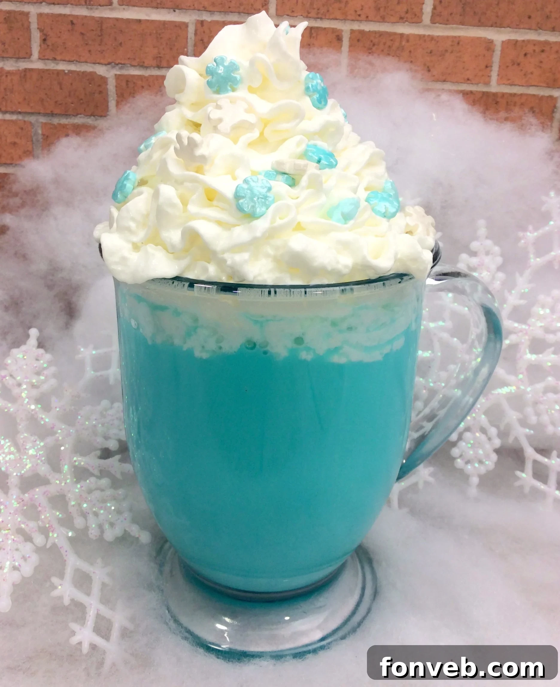 Four mugs of blue hot cocoa, each garnished with whipped cream and various blue and white sprinkles, arranged artfully on a light background.