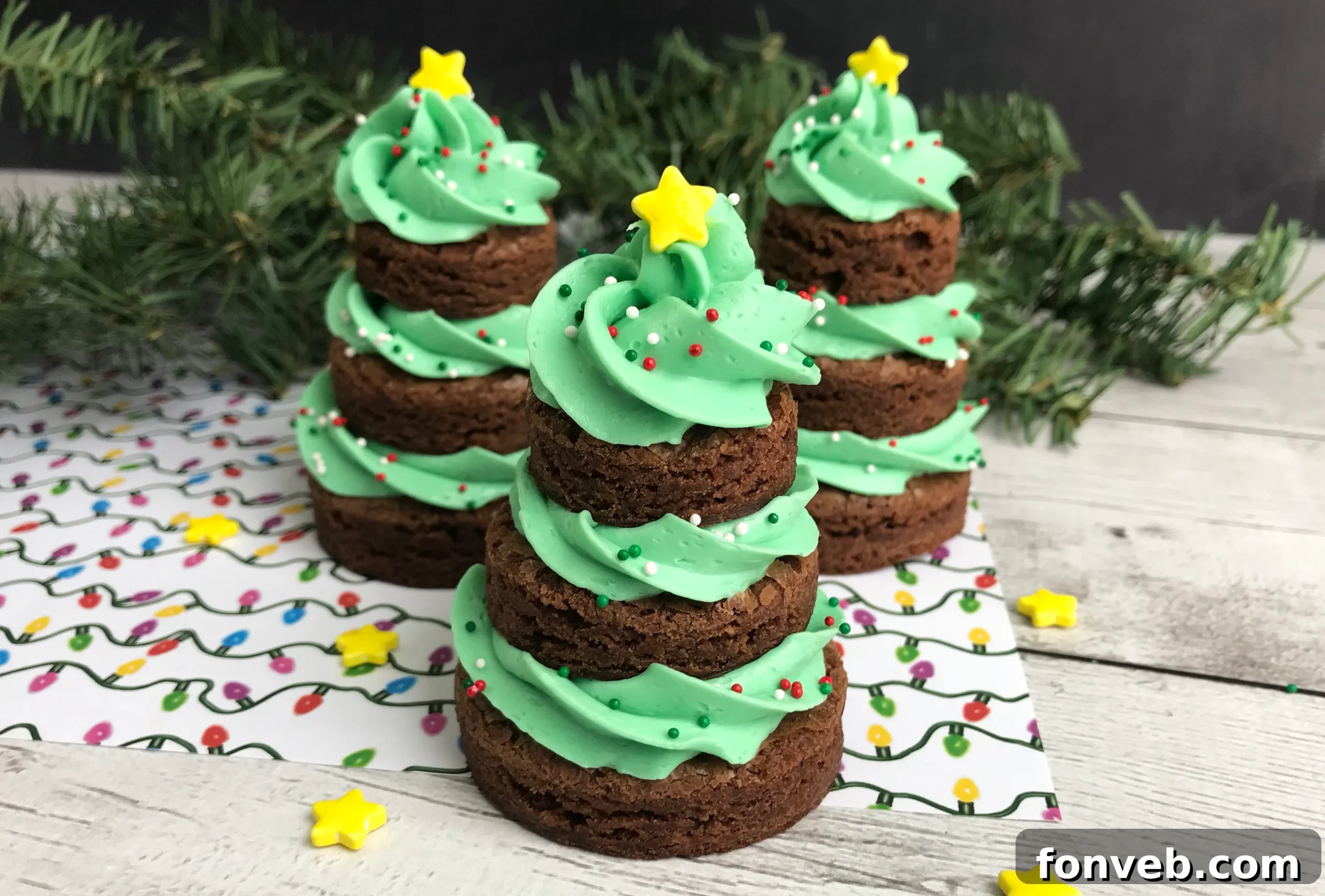 Stacked brownie Christmas trees beautifully decorated with green frosting, festive sprinkles, and a yellow star on top, ready for holiday celebrations.