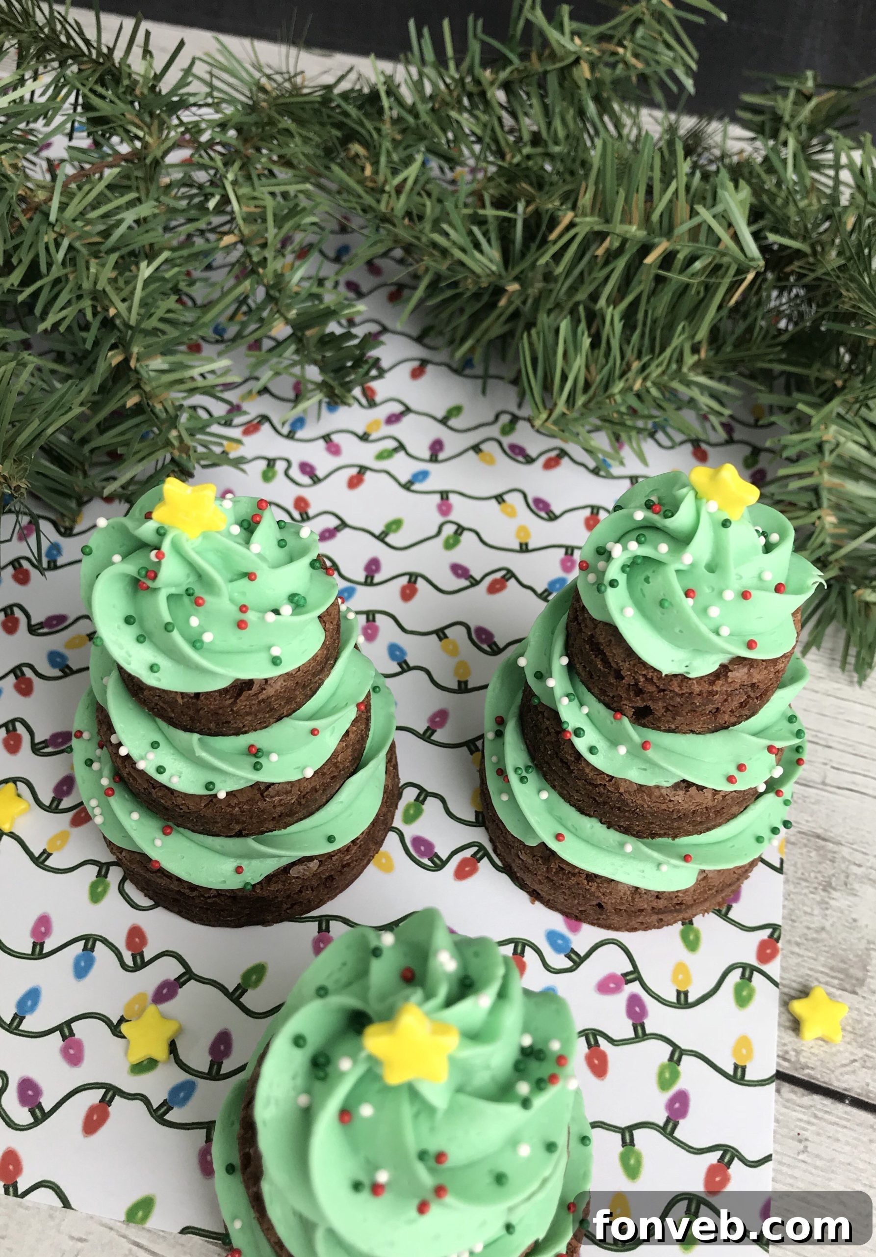 A close-up shot showing the careful process of piping vibrant green frosting onto a stacked brownie tree, illustrating the key decoration step.