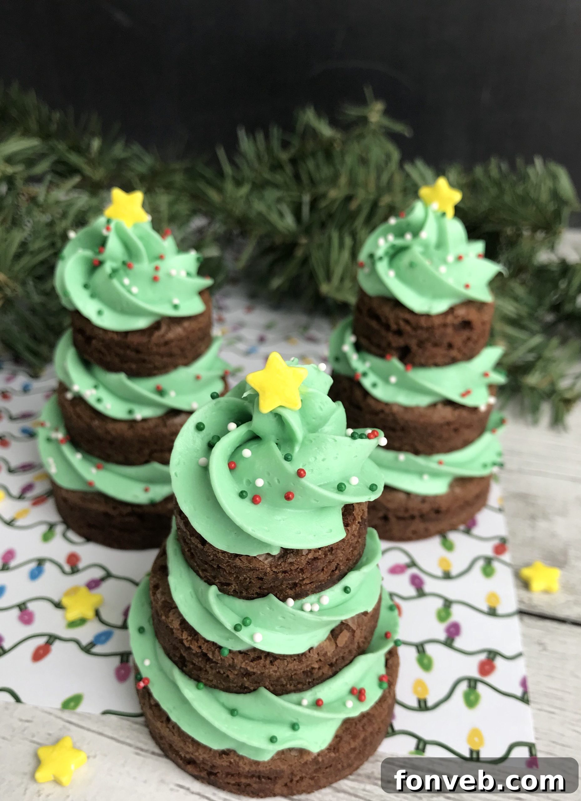 A stunning display of finished Brownie Christmas Trees on a festive plate, adorned with bright green frosting, colorful sprinkles, and yellow stars.