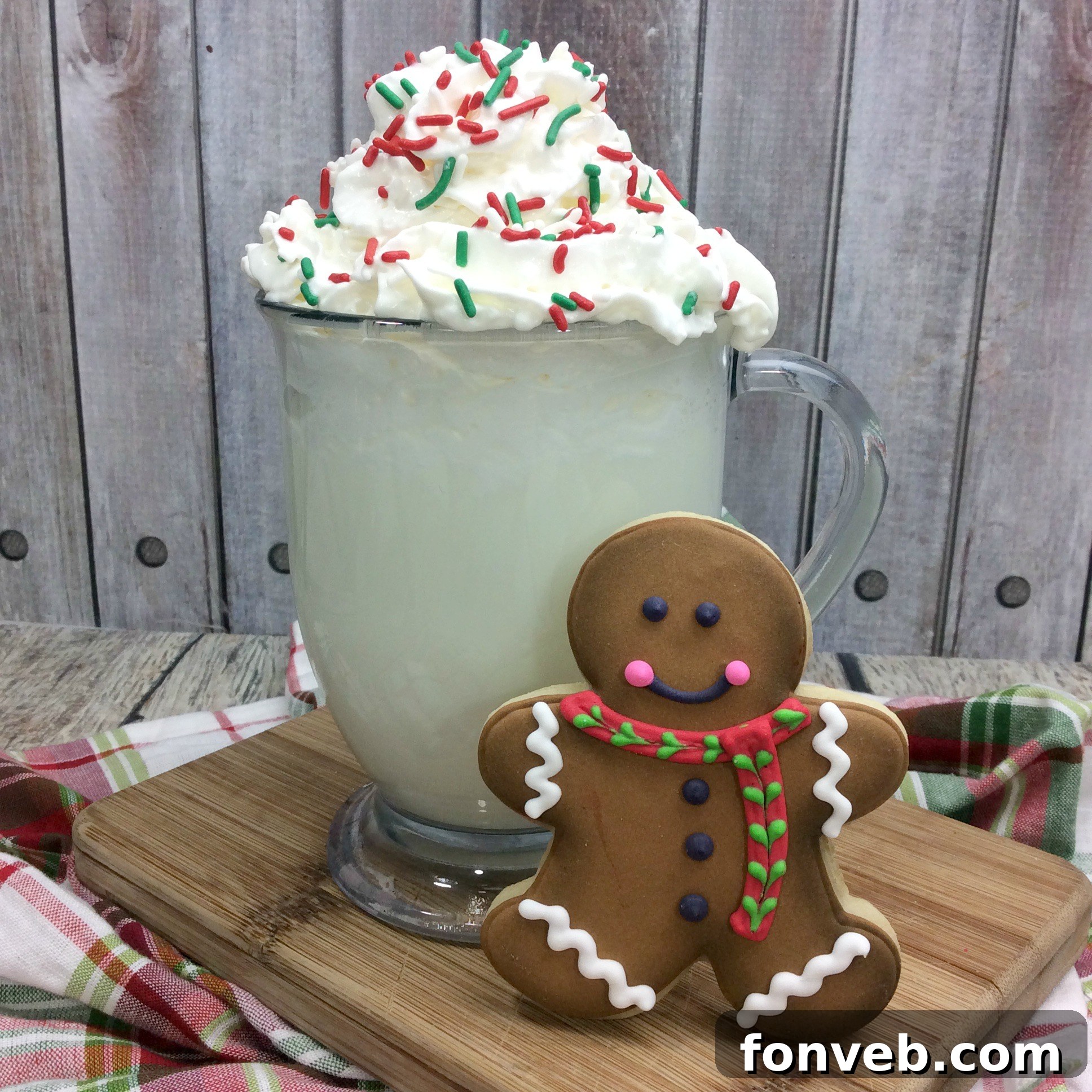 Close-up of two mugs of homemade Sugar Cookie Hot Cocoa, lavishly topped with whipped cream, colorful sprinkles, and mini sugar cookies.