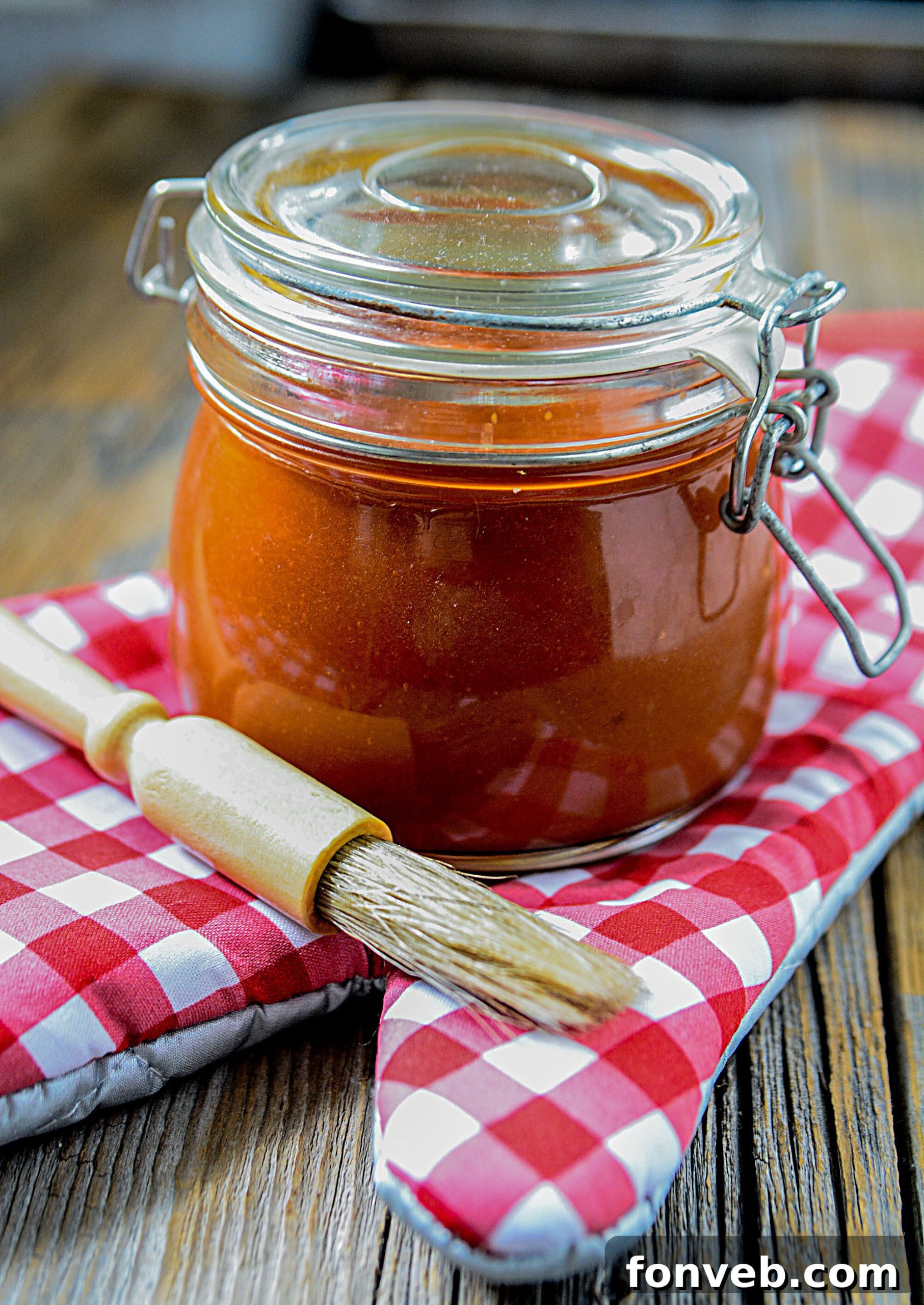 Homemade Root Beer BBQ Sauce in a jar with grilling tools