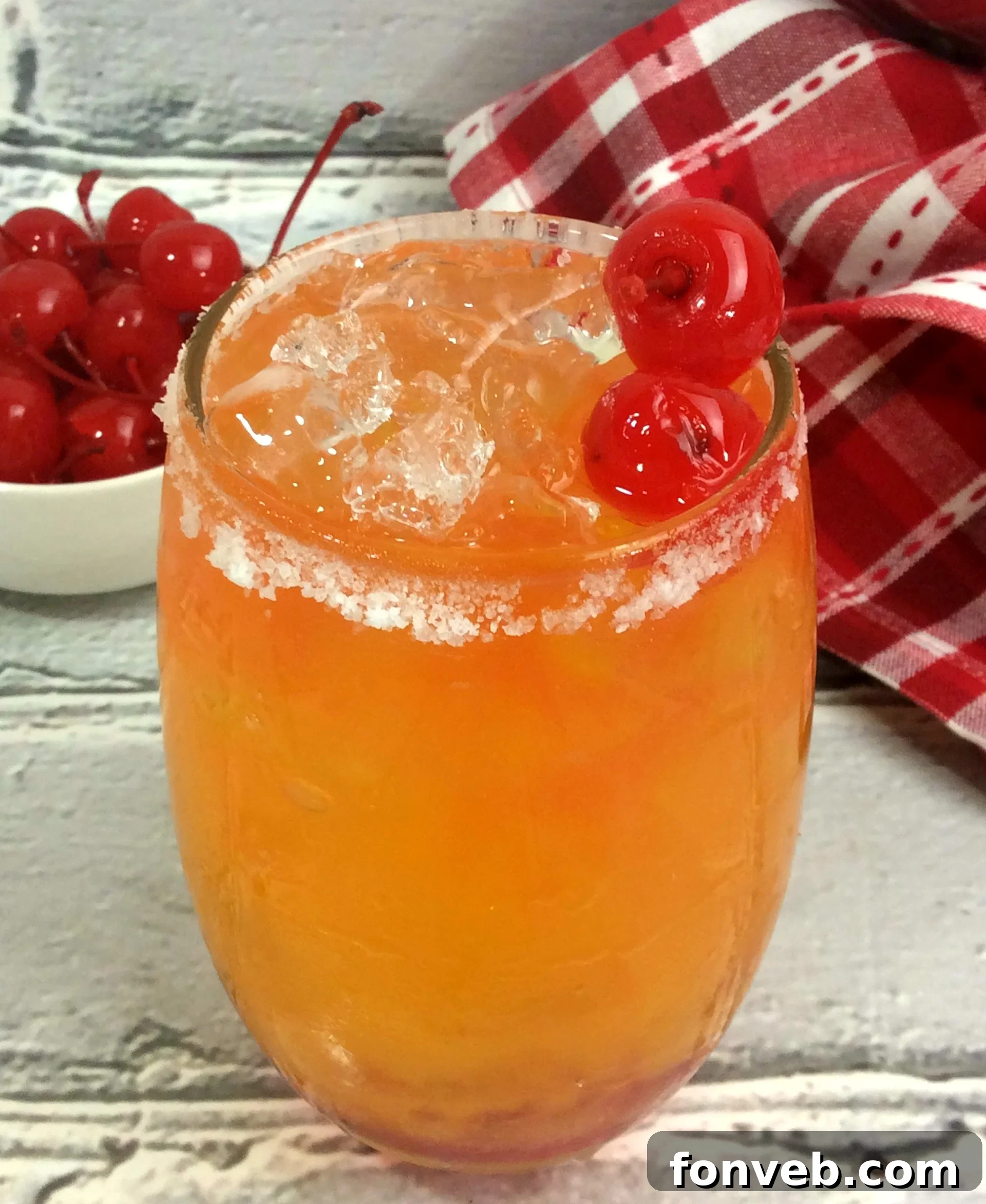 Delicious Take Me on the Couch Cocktail with mango and pineapple flavors, garnished with lime and cherry.