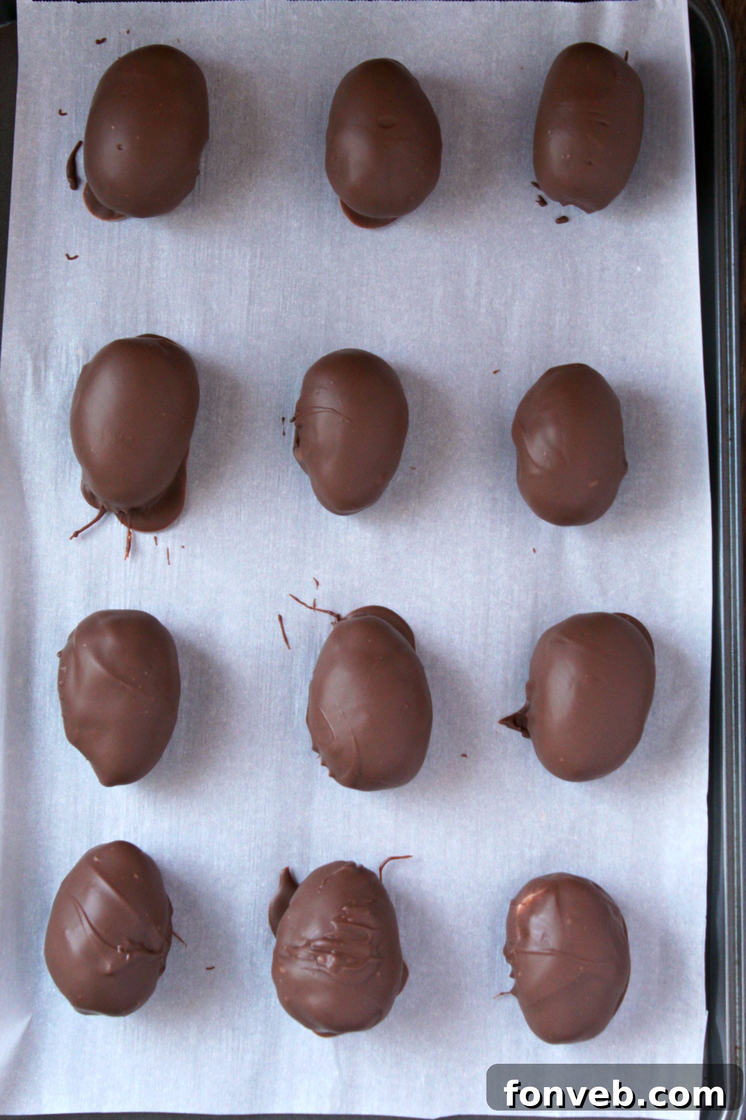 Hand shaping the coconut mixture into an egg form on a parchment-lined baking sheet