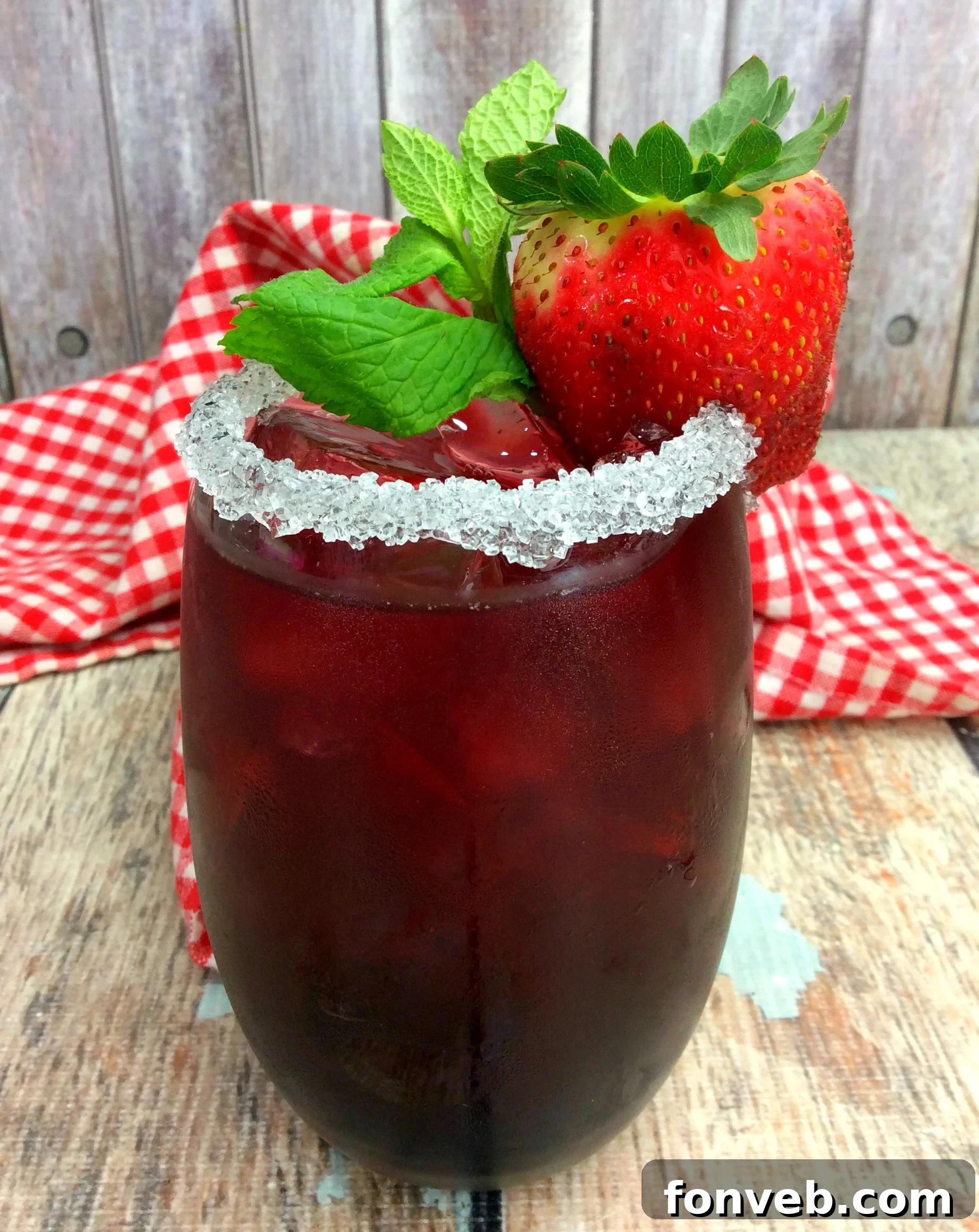 Tickle Me Strawberry Triple Crown Cocktail in a glass with strawberries and mint garnish.