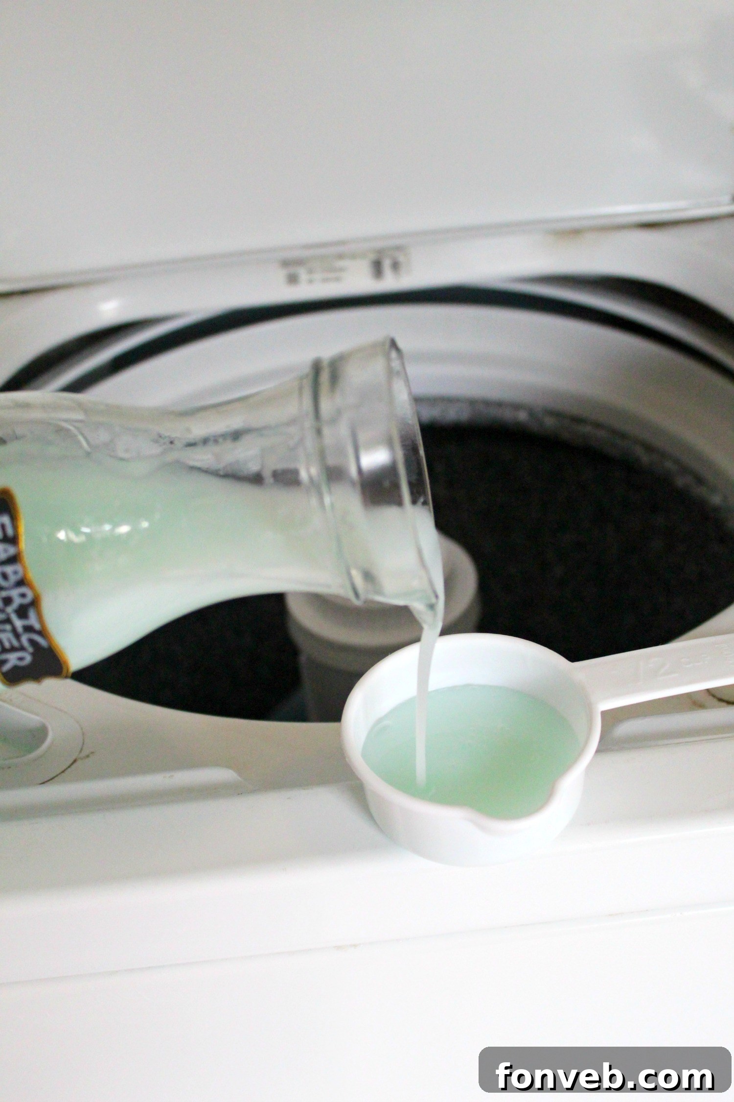 Bottle of white vinegar and a measuring cup, ready for mixing