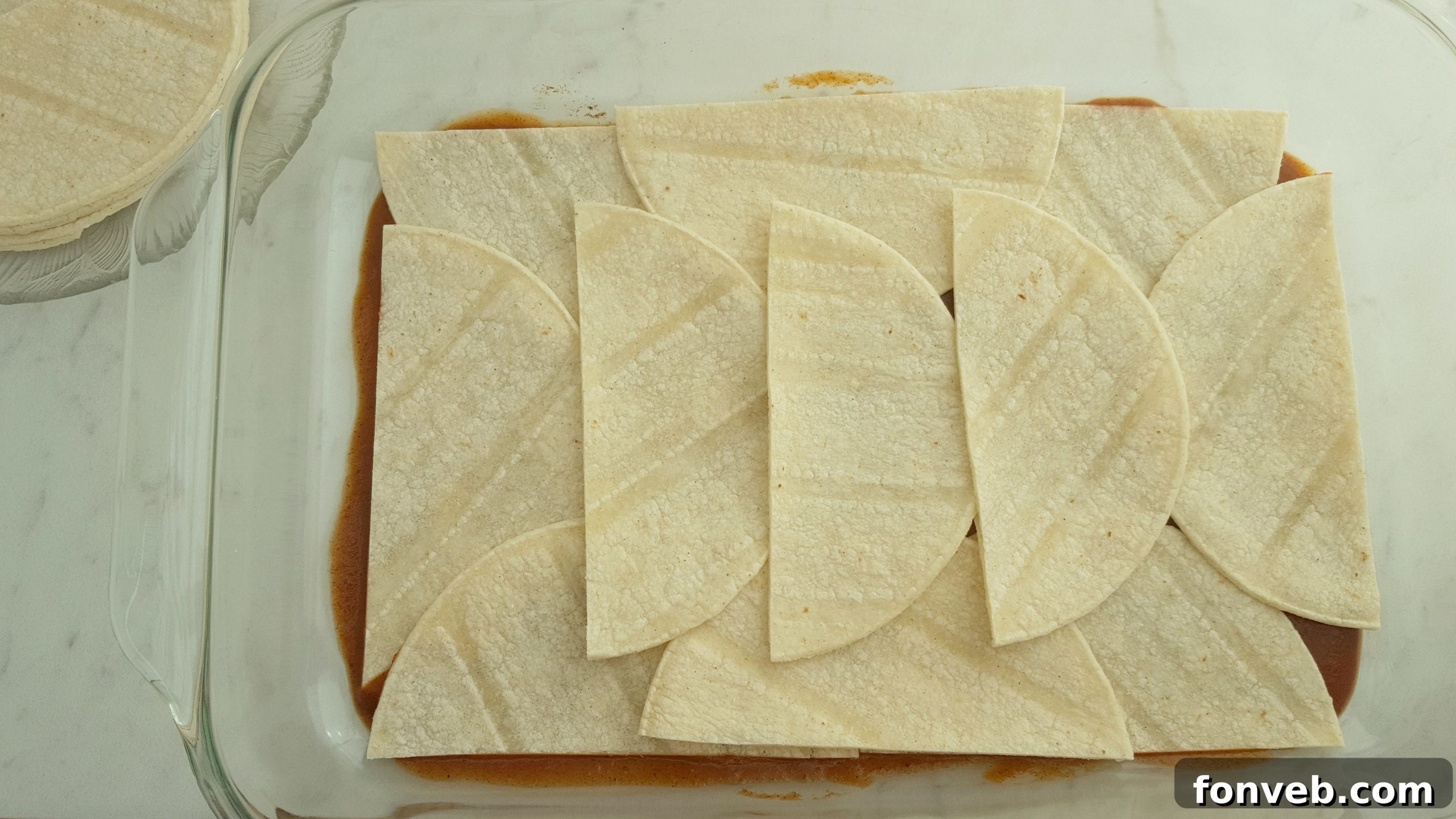 Building the layers of Mexican Lasagna with meat, beans, and cheese.