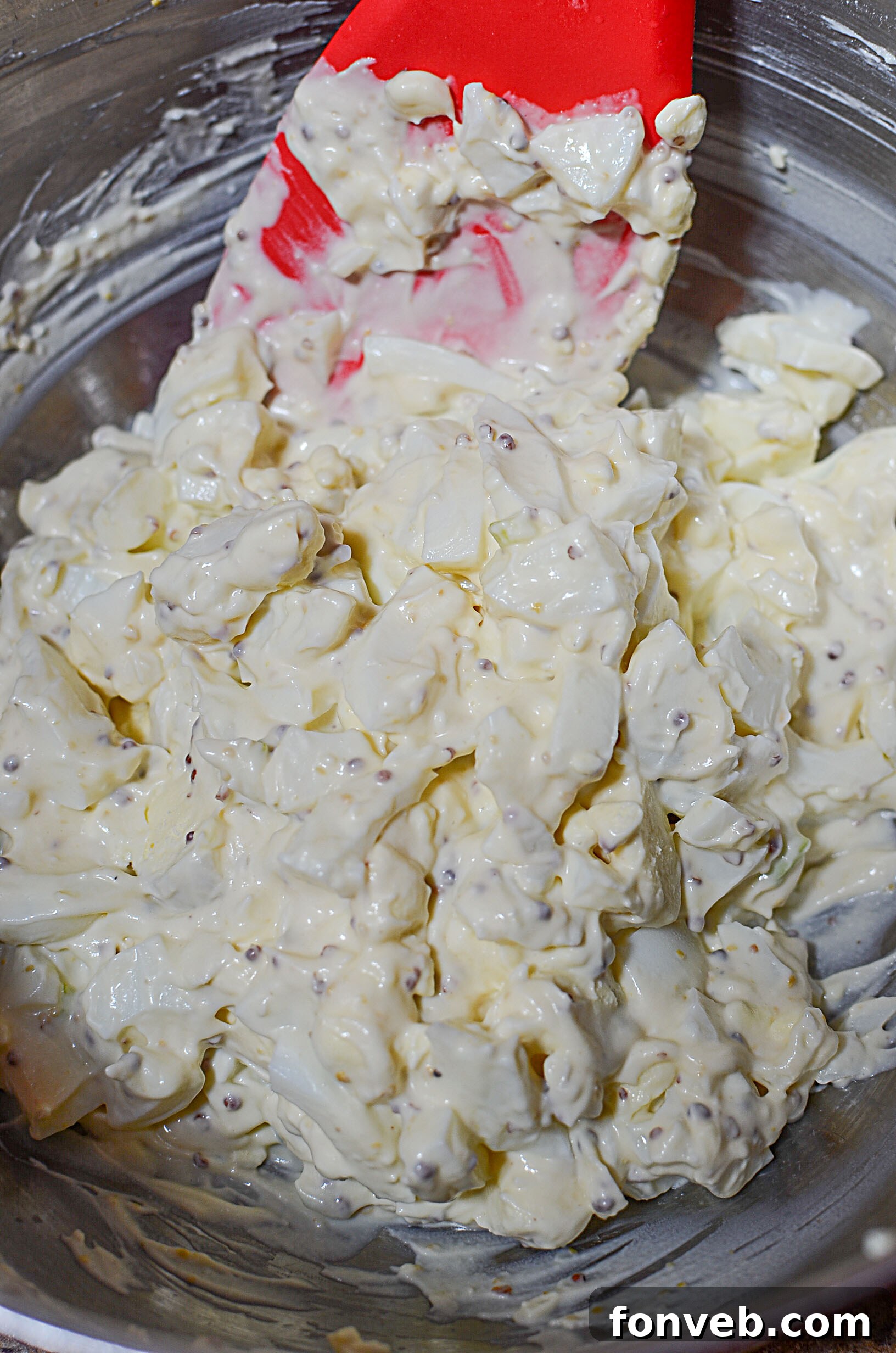 A spoonful of creamy egg salad with visible seasonings and onion.