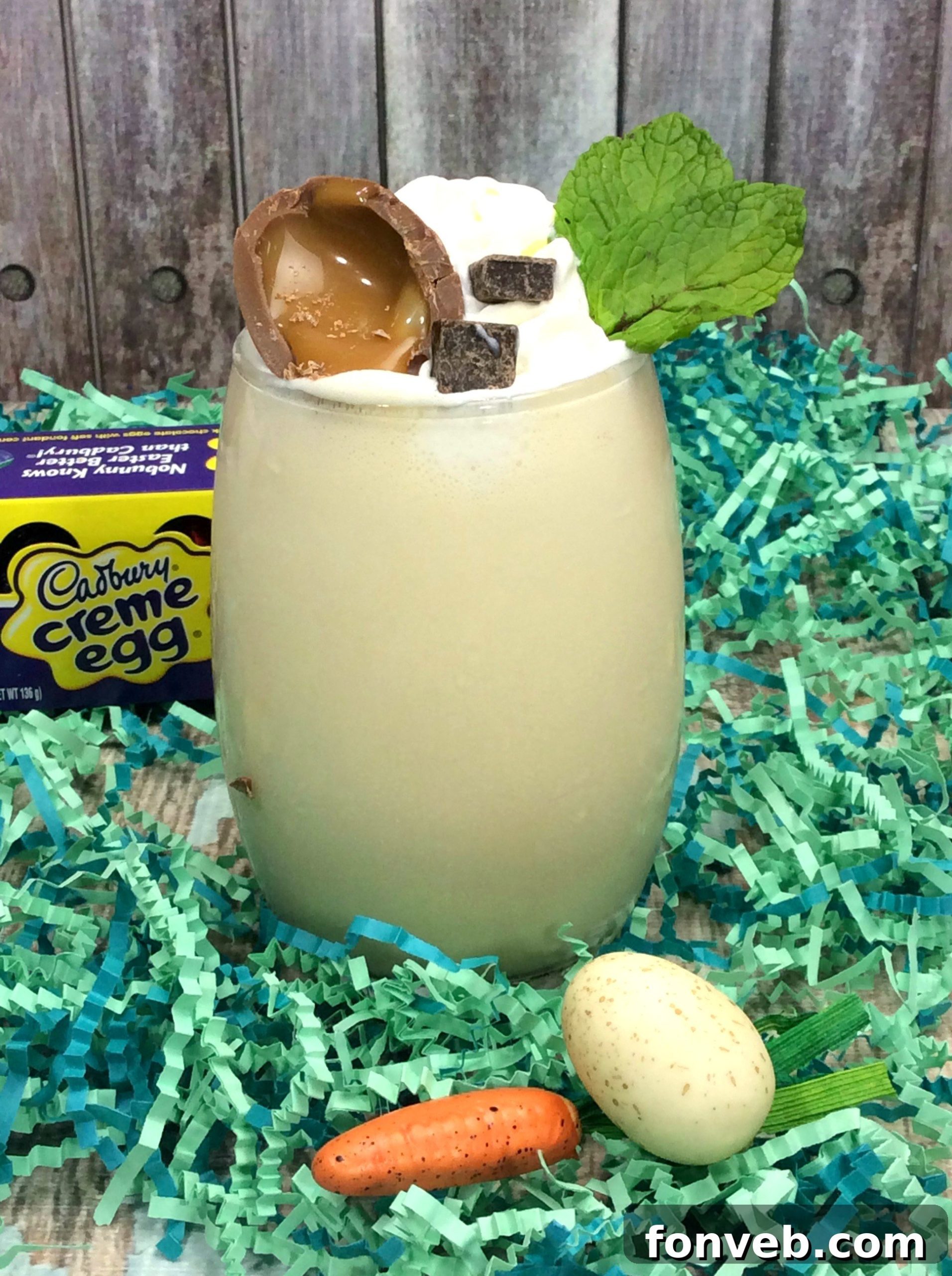 A vibrant Cadbury Creme Egg Cocktail in a glass, topped with whipped cream and a chocolate egg garnish.