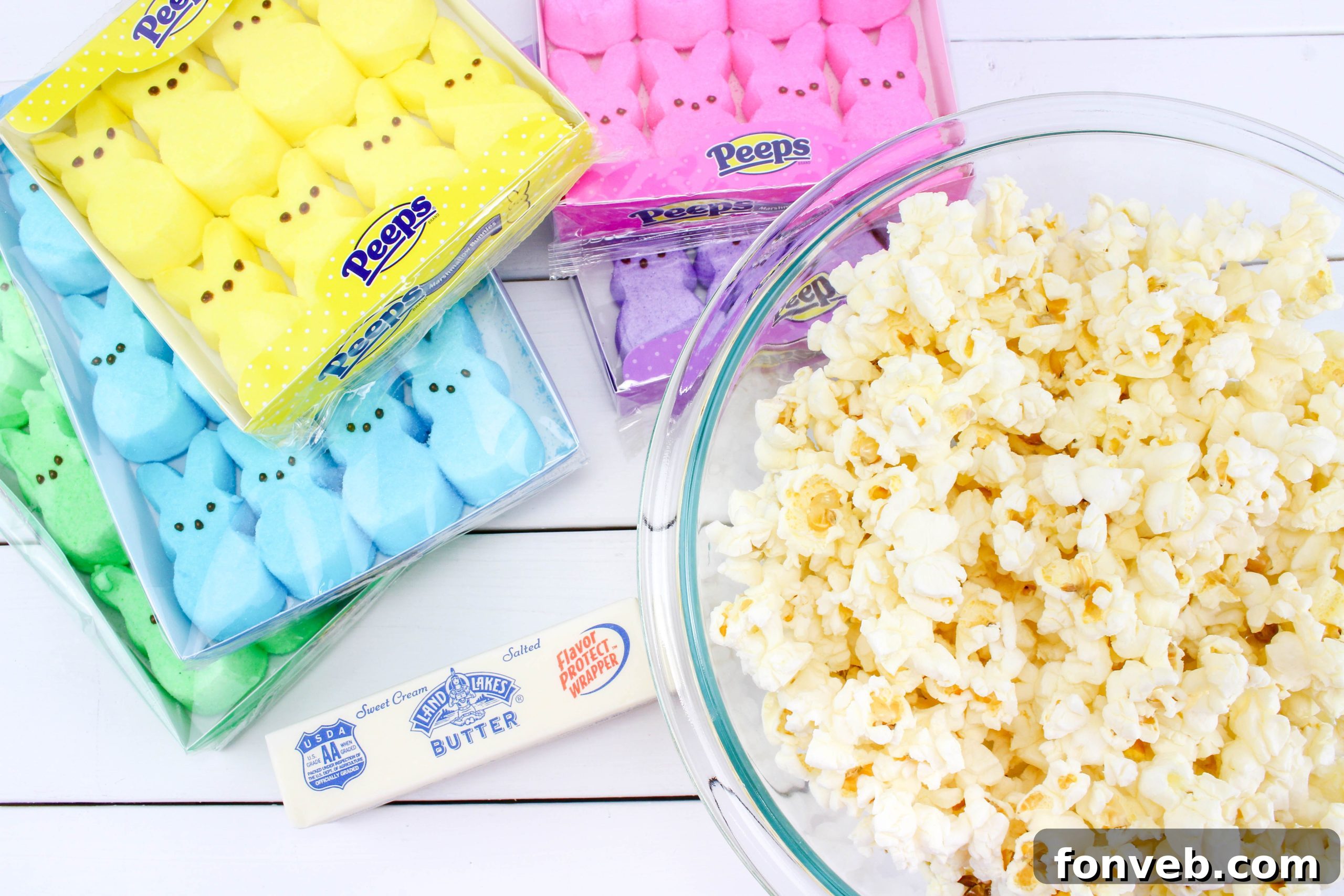 Close-up of fluffy, rainbow-colored marshmallow mixture being stirred with popcorn in a large bowl, demonstrating the preparation process.