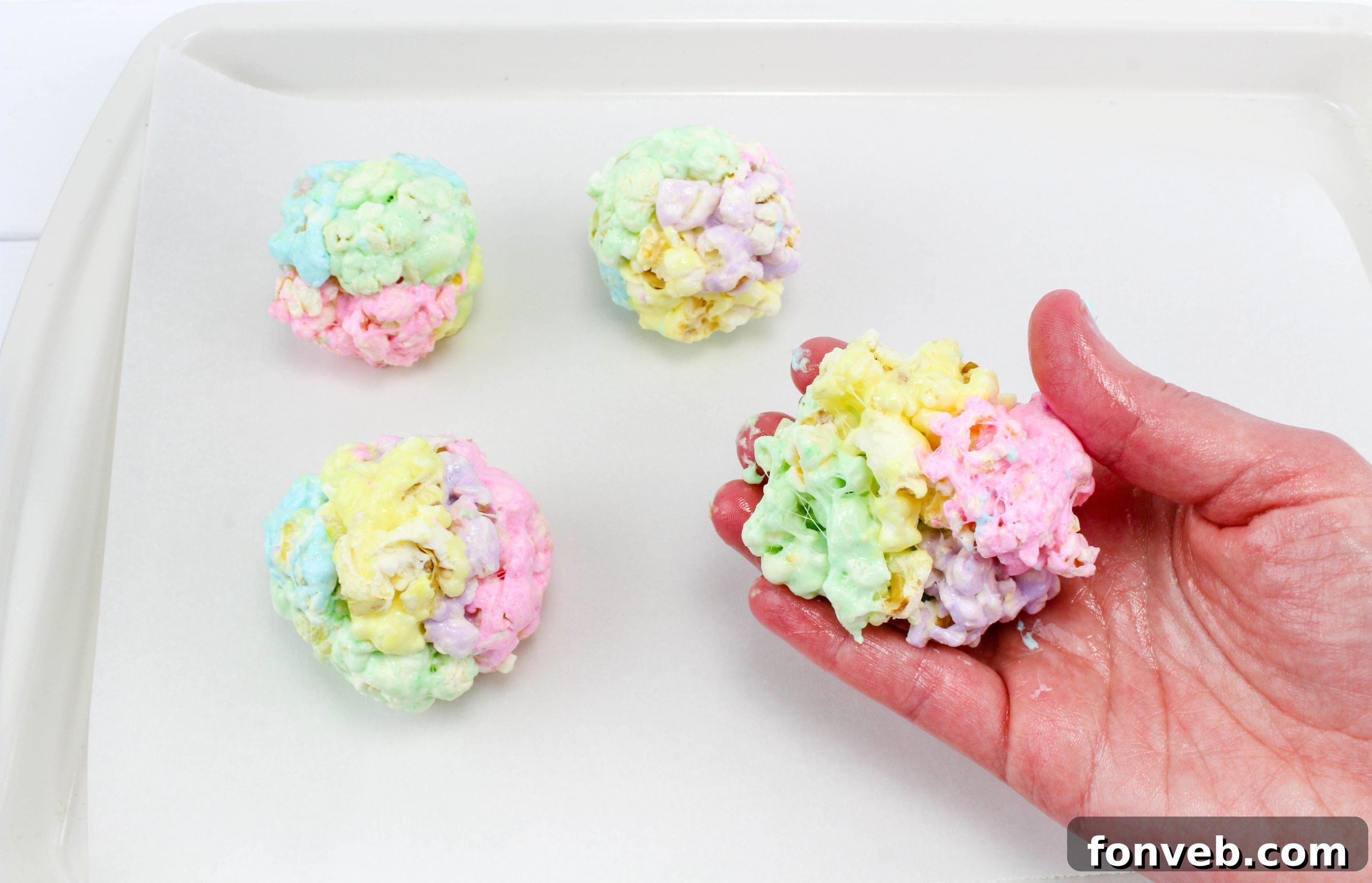 An assortment of vibrant marshmallow popcorn balls, individually wrapped in clear cellophane and tied with ribbons, ready for gifting or sharing.