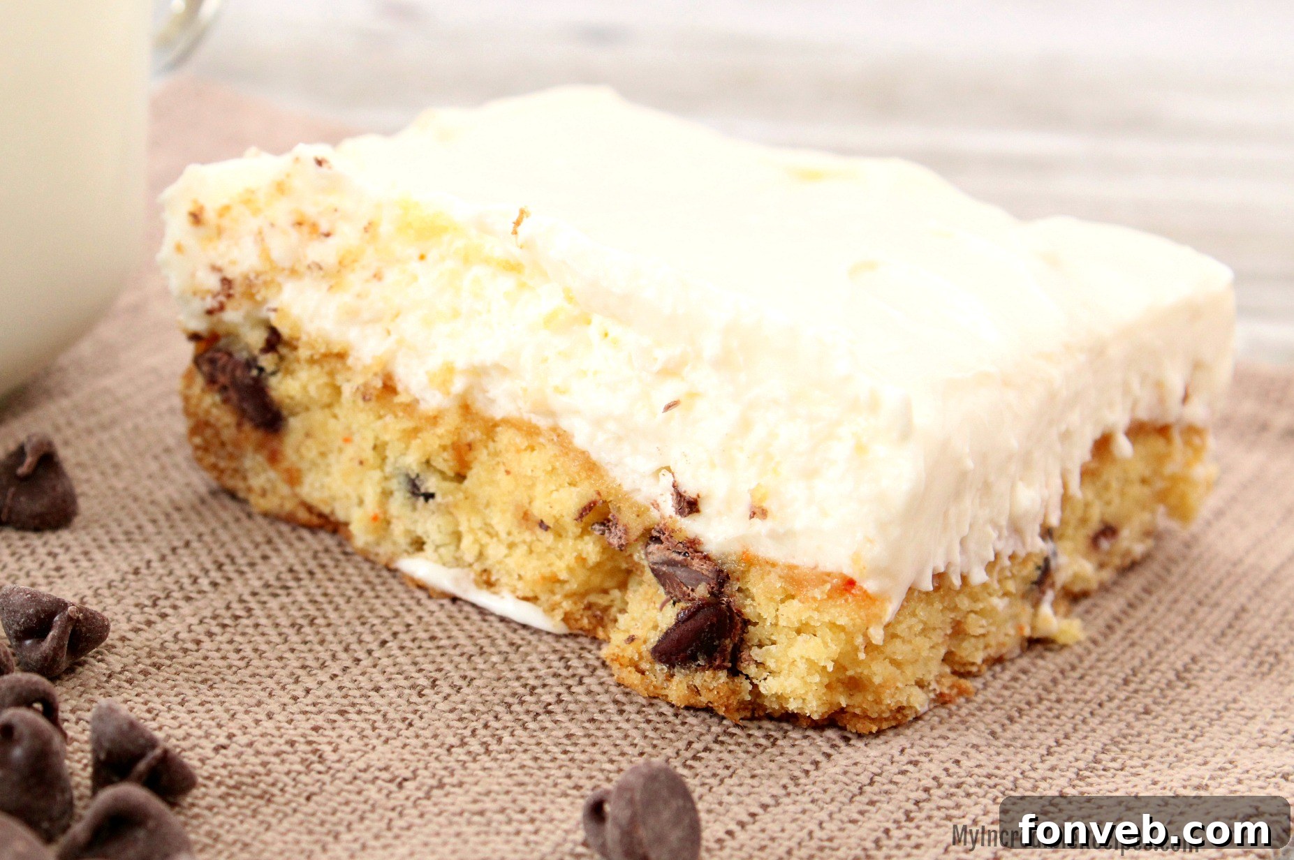 A top-down view of freshly baked Toll House Chocolate Chip Cheesecake Bars, glistening with melted chocolate, ready to be chilled and sliced.
