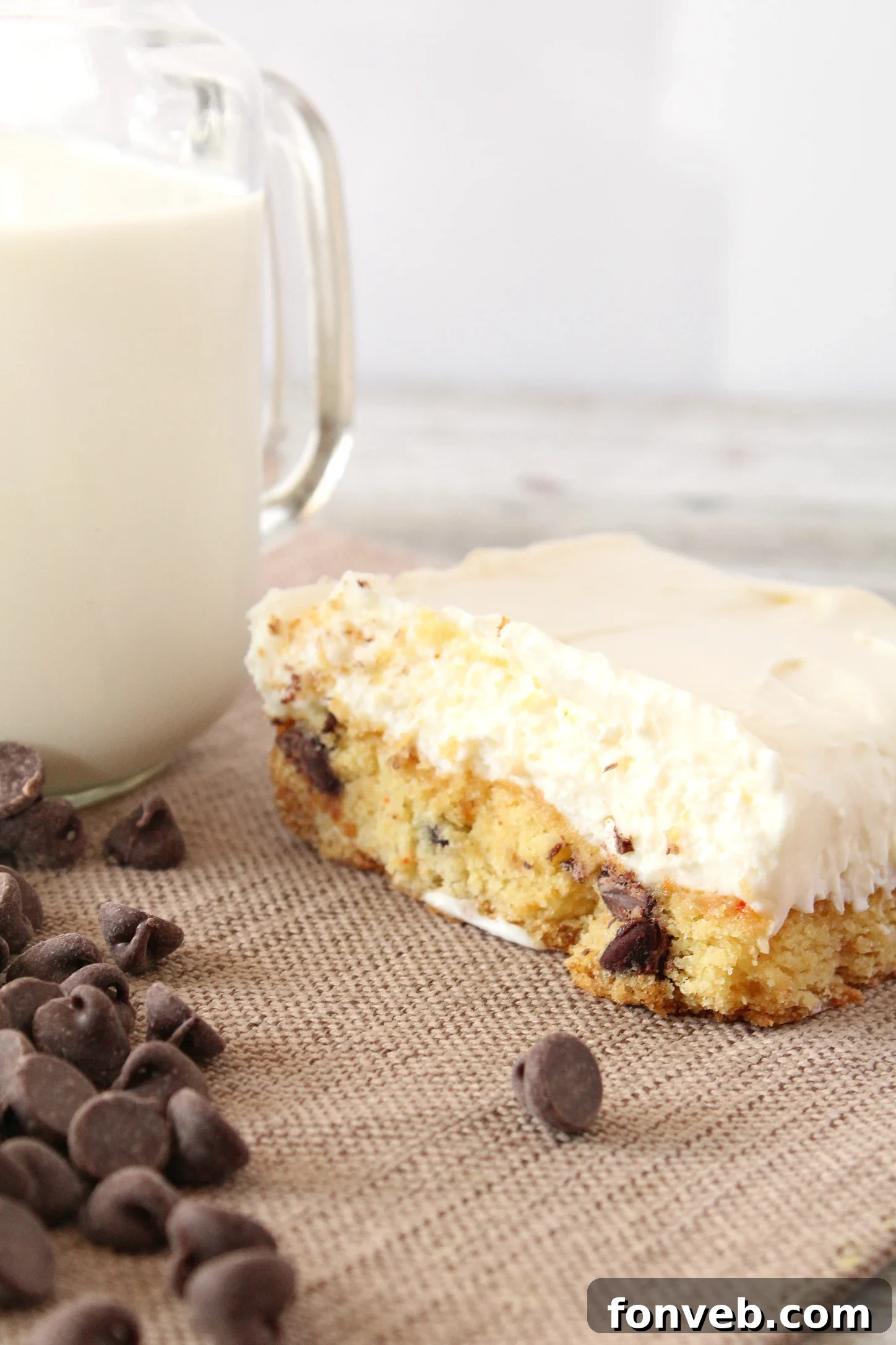 A close-up shot of a single, perfectly cut Toll House Chocolate Chip Cheesecake Bar, highlighting the thick, chewy cookie base and the generous, creamy cheesecake topping.