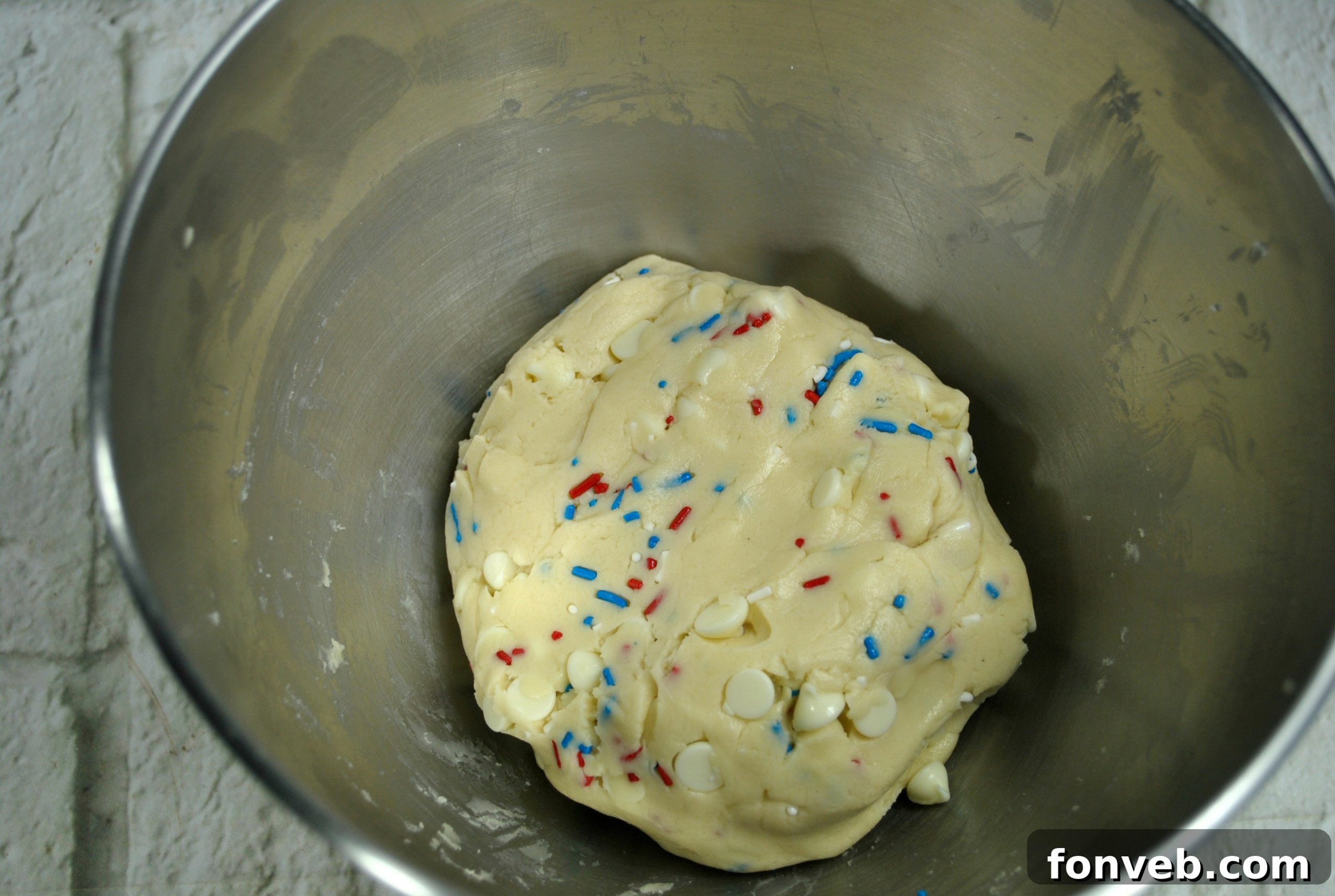 Unbaked cookie dough infused with colorful sprinkles, showing its readiness to be scooped and baked into delicious treats.