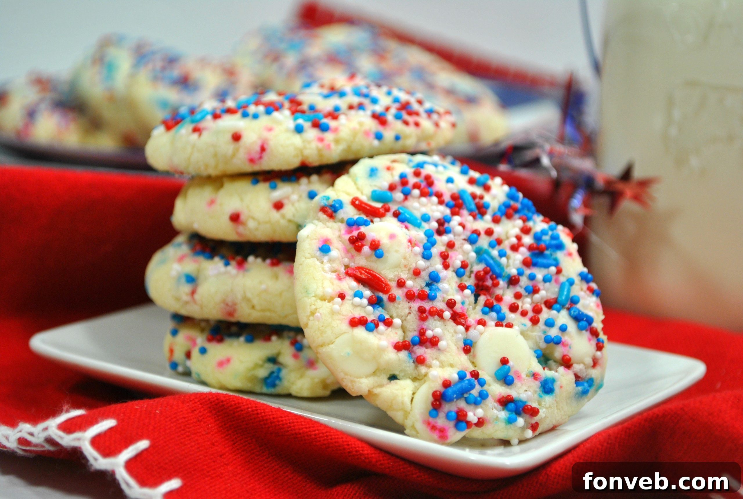 A stack of colorful White Chocolate Firework Cookies next to a refreshing glass of milk, inviting for a treat.