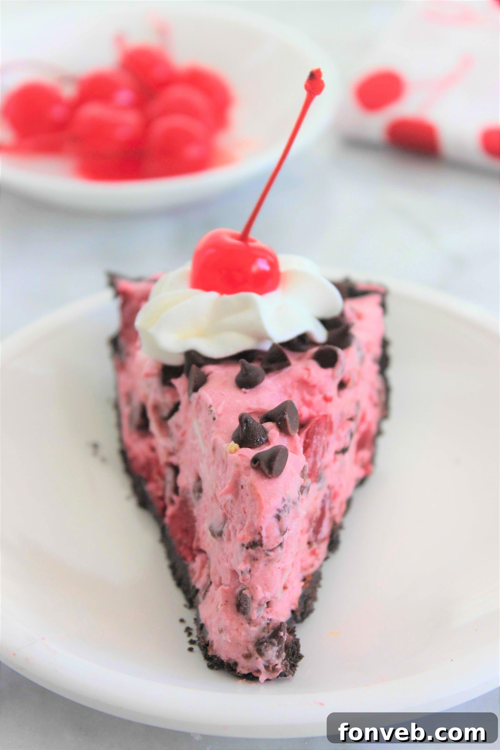 Close-up of a slice of No-Bake Cherry Creamsicle Pie, showing its creamy texture and chocolate chip filling