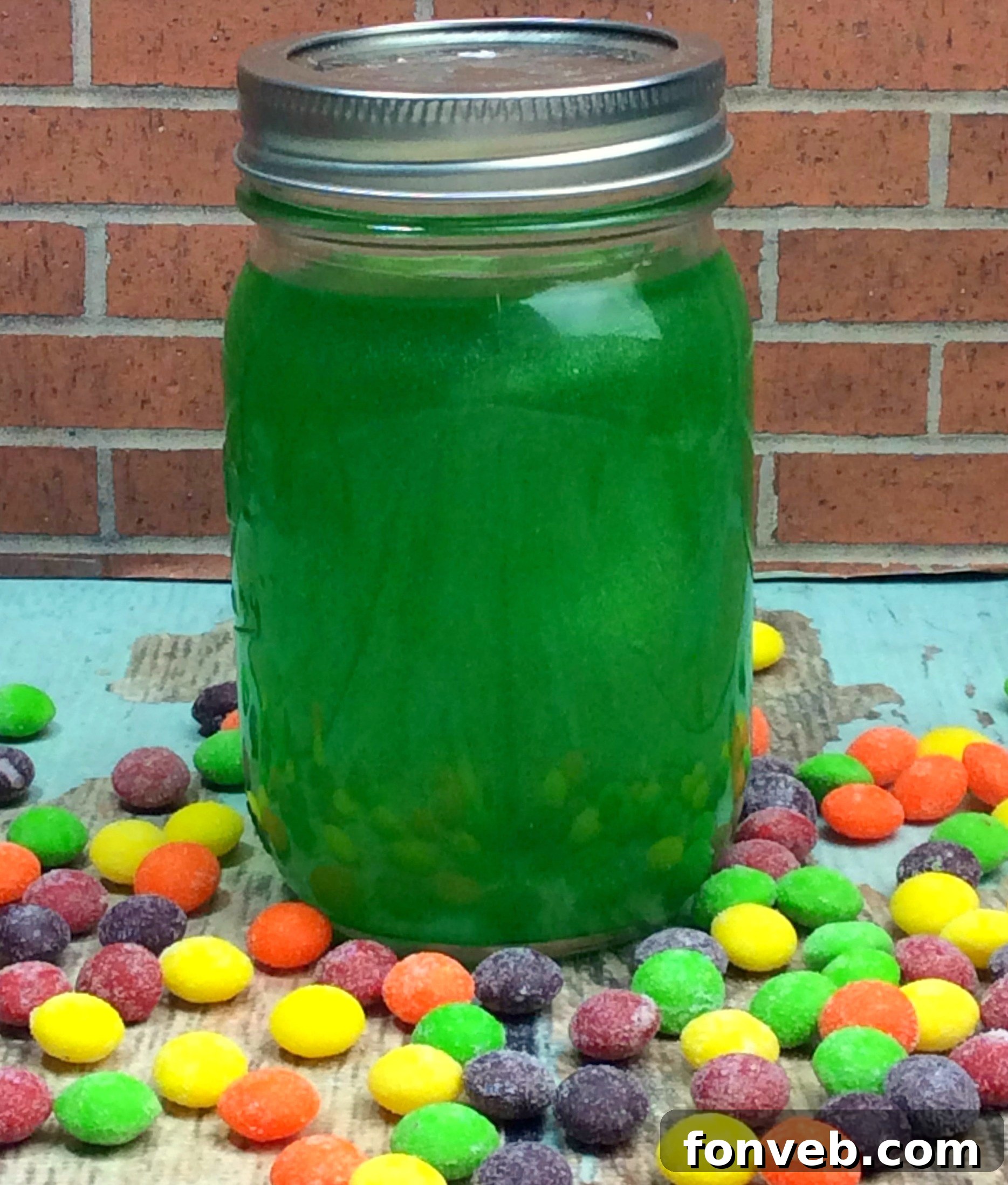 Close-up of Skittles dissolving in Everclear inside a mason jar, showing the color infusion