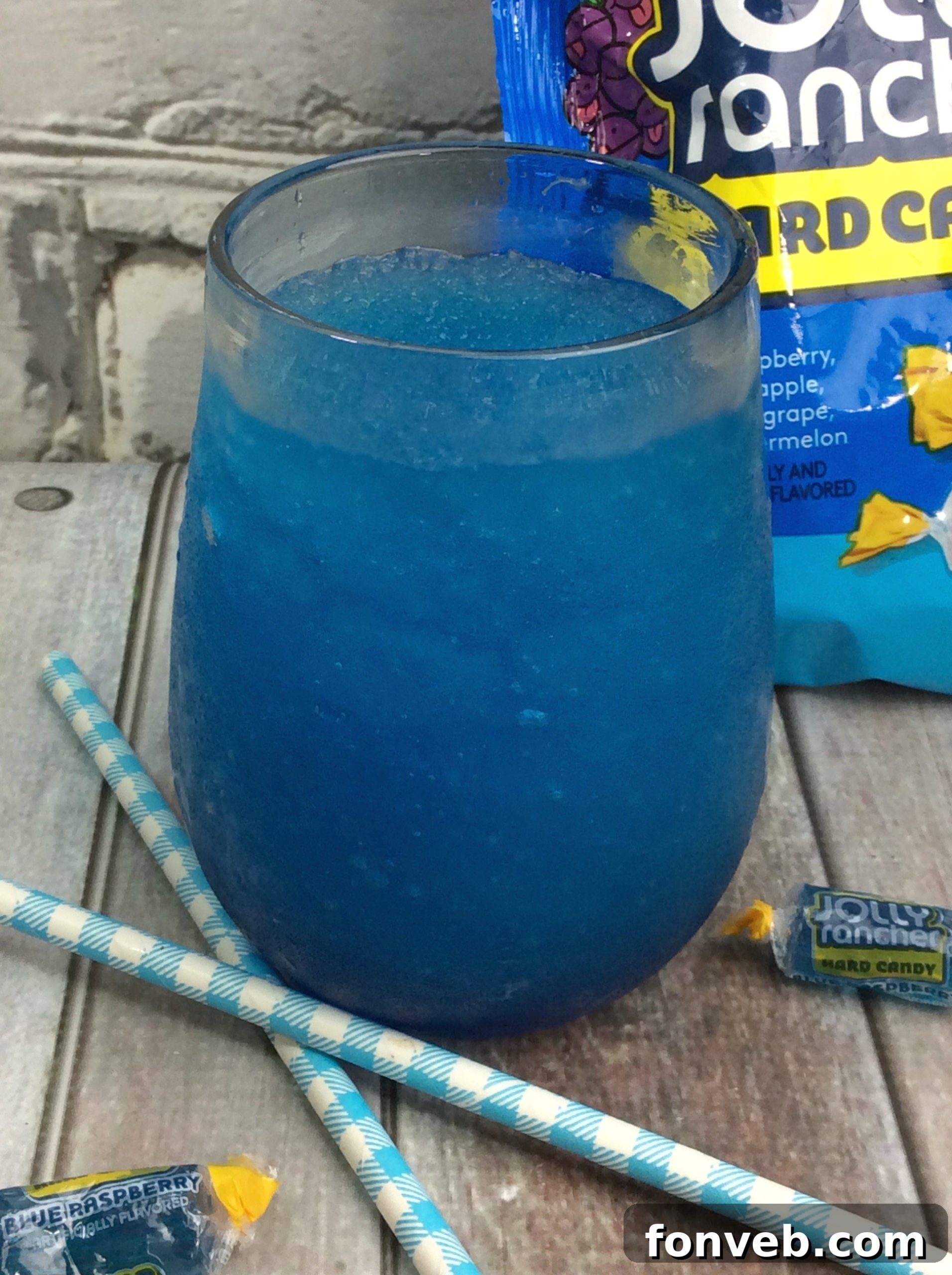A close-up of a blender filled with blue slushy cocktail ingredients