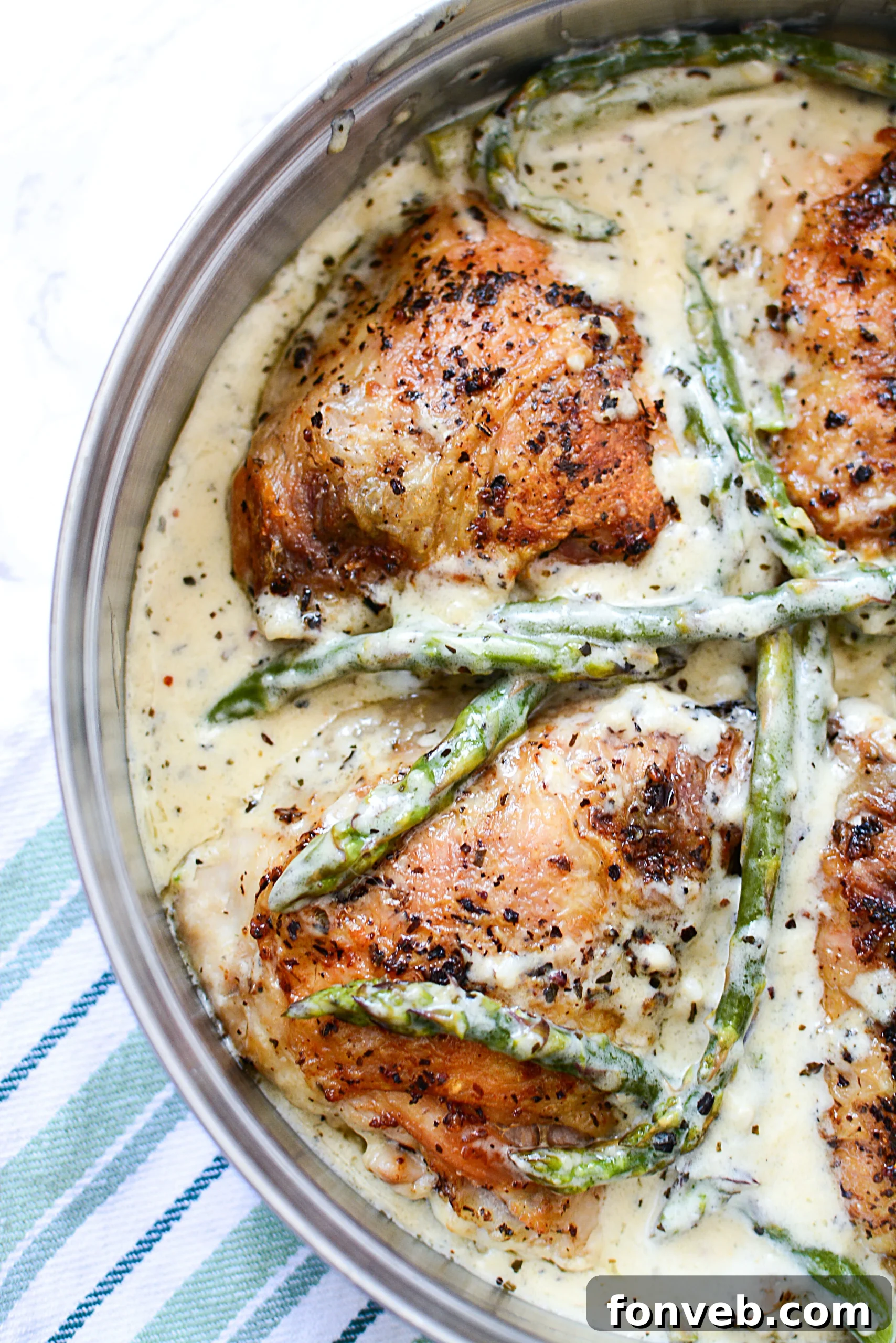An overhead shot showcasing the vibrant green asparagus alongside the creamy garlic chicken in a cast iron skillet