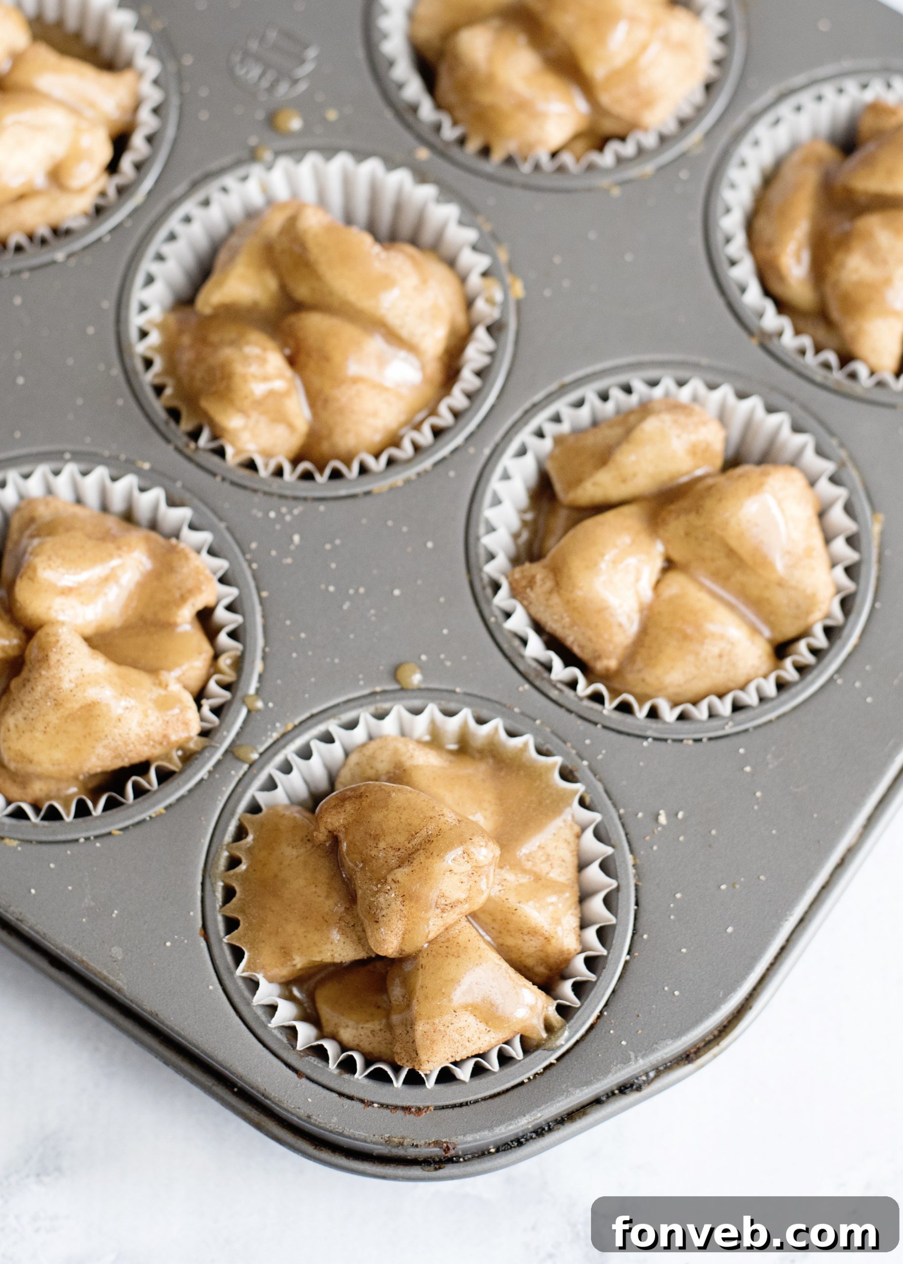Irresistible Snickerdoodle Pull-Apart Muffins 5 Hands placing cinnamon-sugar coated biscuit pieces into a muffin liner, showcasing the assembly process.