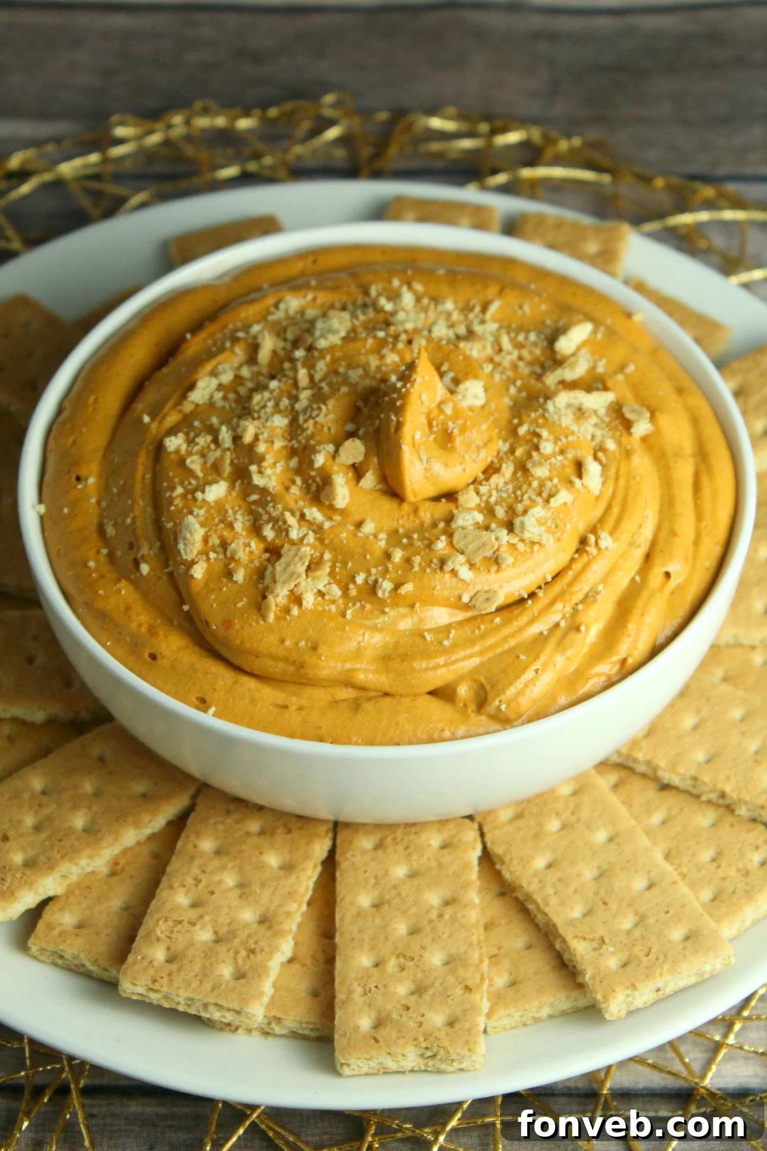 An overhead shot of the pumpkin pie cheesecake dip, perfectly creamy and inviting, surrounded by a variety of dippers including graham crackers, Nilla wafers, and sugar cookies.