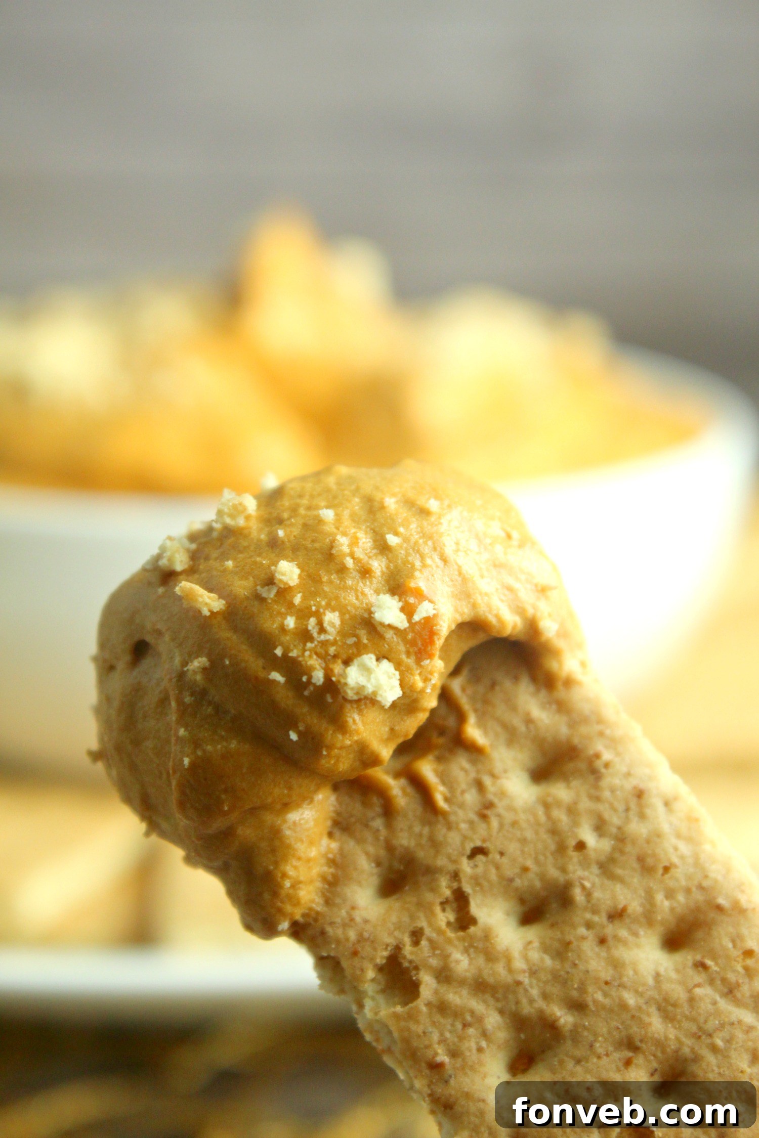 A serving spoon gracefully scooping a generous portion of the rich and creamy pumpkin pie cheesecake dip, emphasizing its desirable consistency.