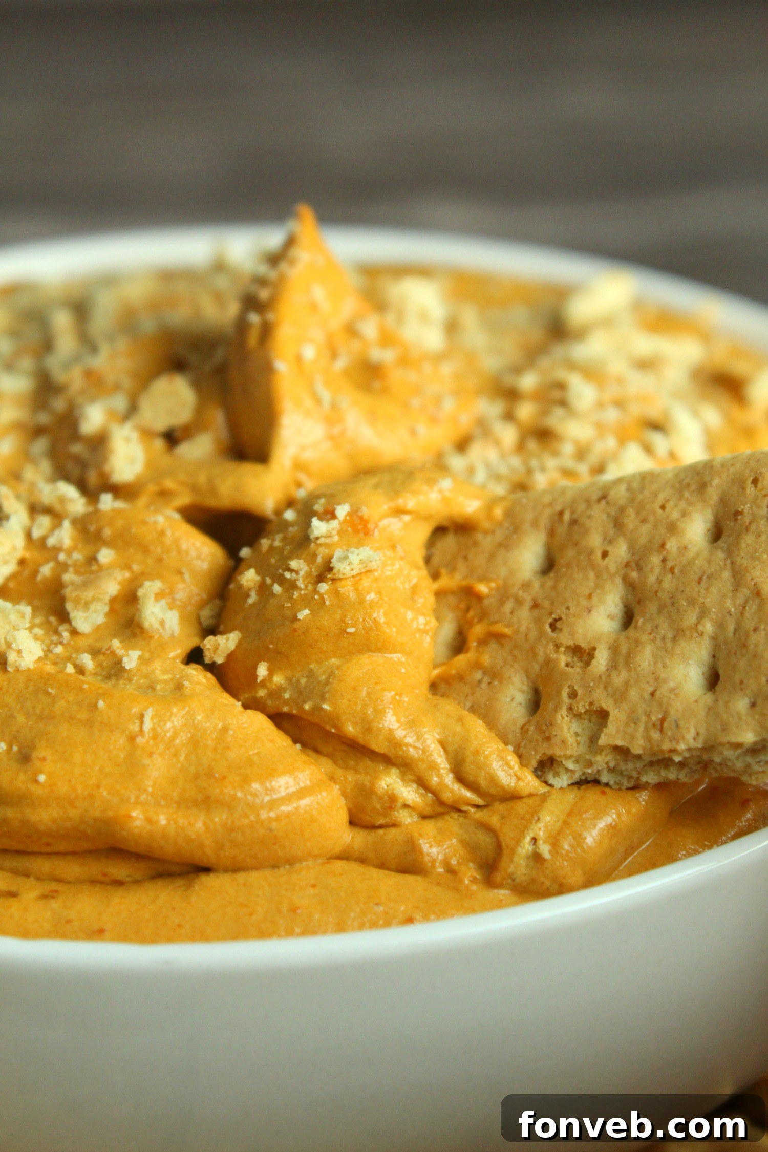 A wide shot of the pumpkin pie cheesecake dip presentation, showcasing a full serving bowl surrounded by an array of dippers on a beautifully arranged table, evoking a festive fall atmosphere.
